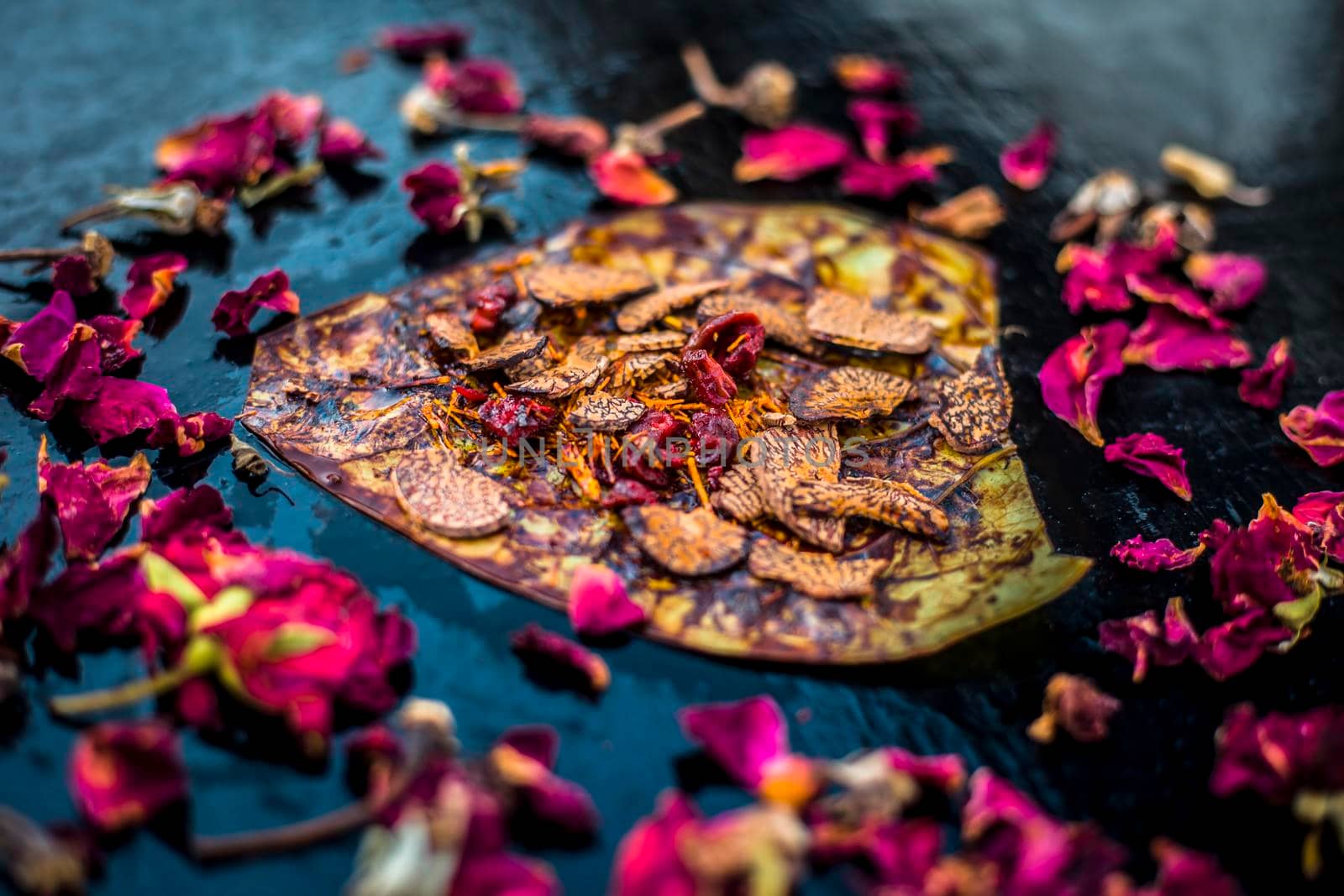 Close up of Famous Indian traditional masala pan or meetha pan on black surface with some rose water consisting of coated sauf,supari,sweeteners and some coconut powder. by mirzamlk