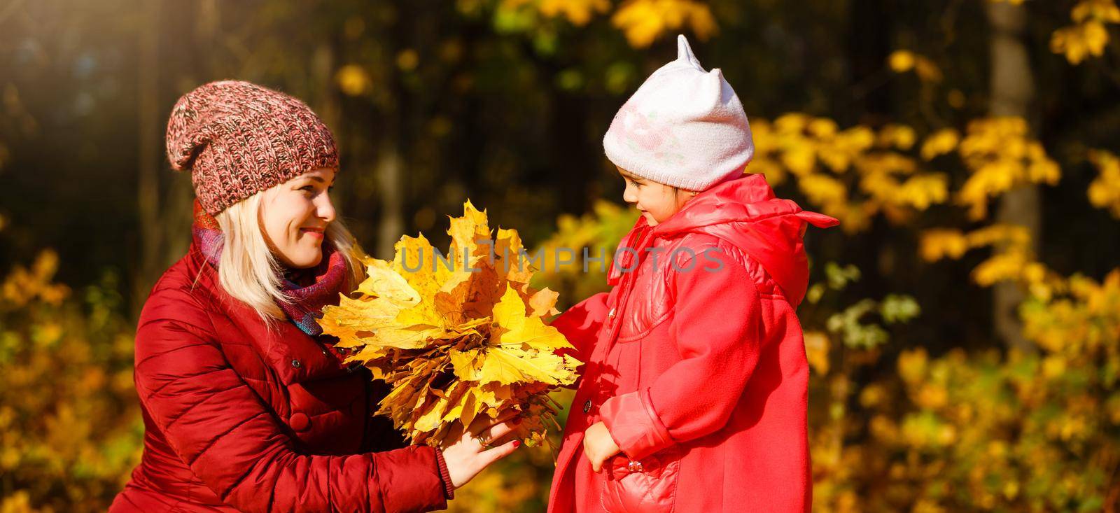 happy family: mother and child little daughter play cuddling on autumn walk in nature outdoors