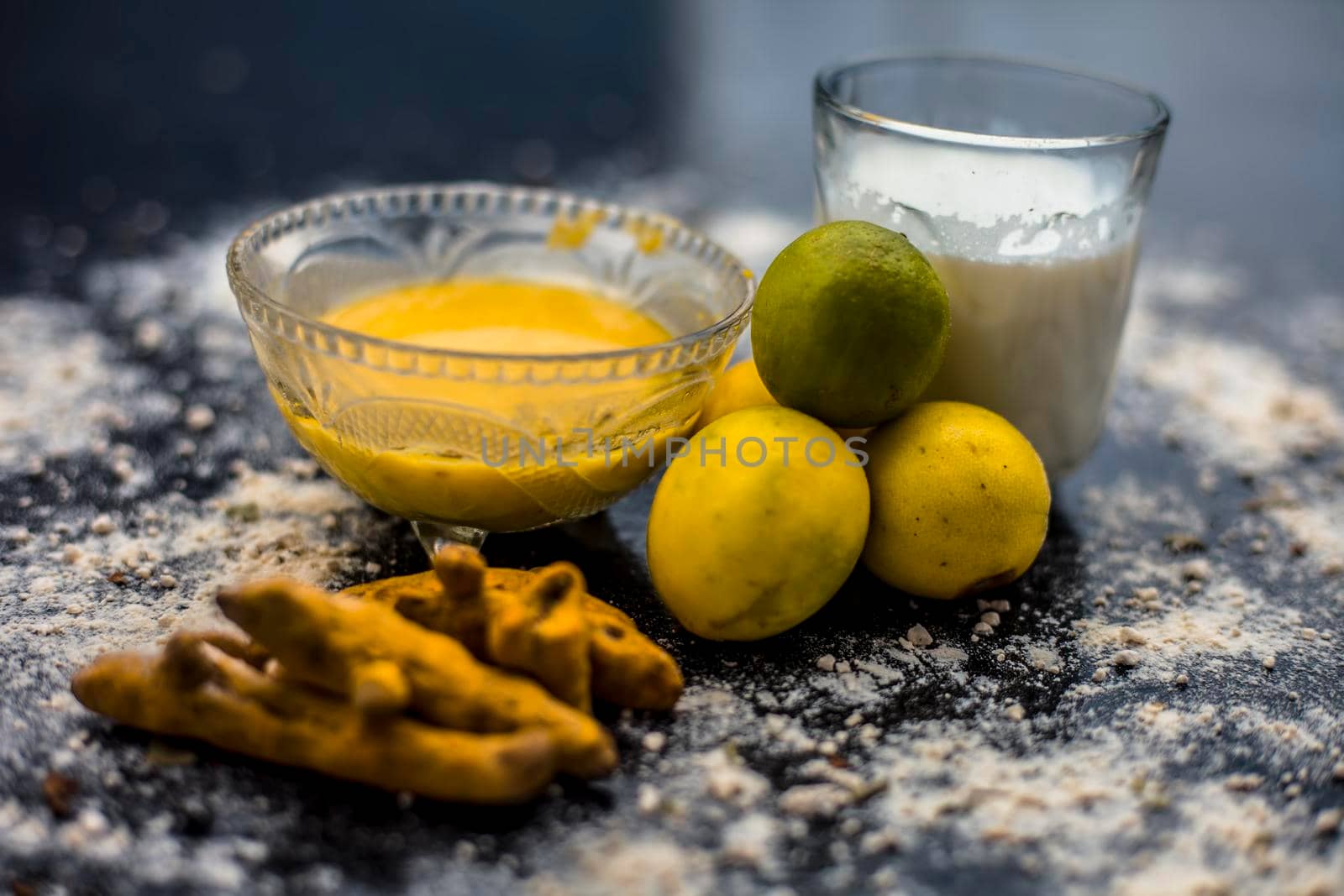 Lemon face mask on the wooden surface consisting lemon juice, gram flour or chickpea flour, turmeric or Haldi and milk in a glass bowl.For the treatment of tans. by mirzamlk