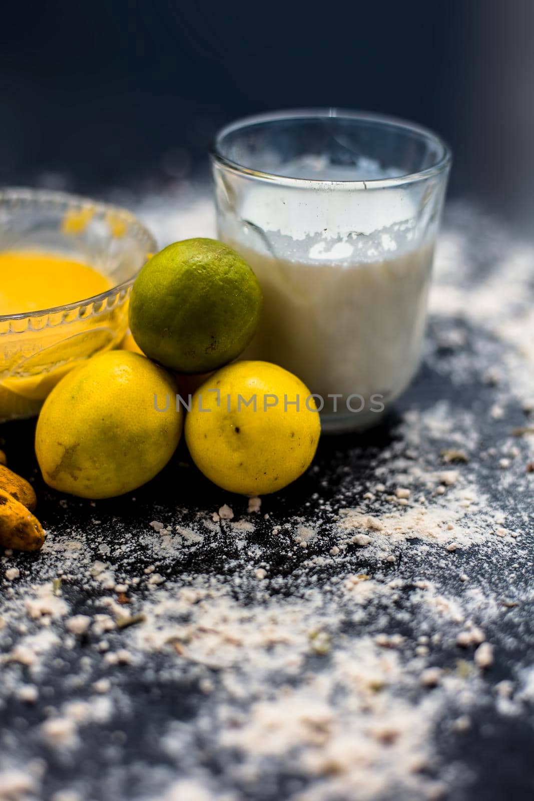 Lemon face mask on the wooden surface consisting lemon juice, gram flour or chickpea flour, turmeric or Haldi and milk in a glass bowl.For the treatment of tans.