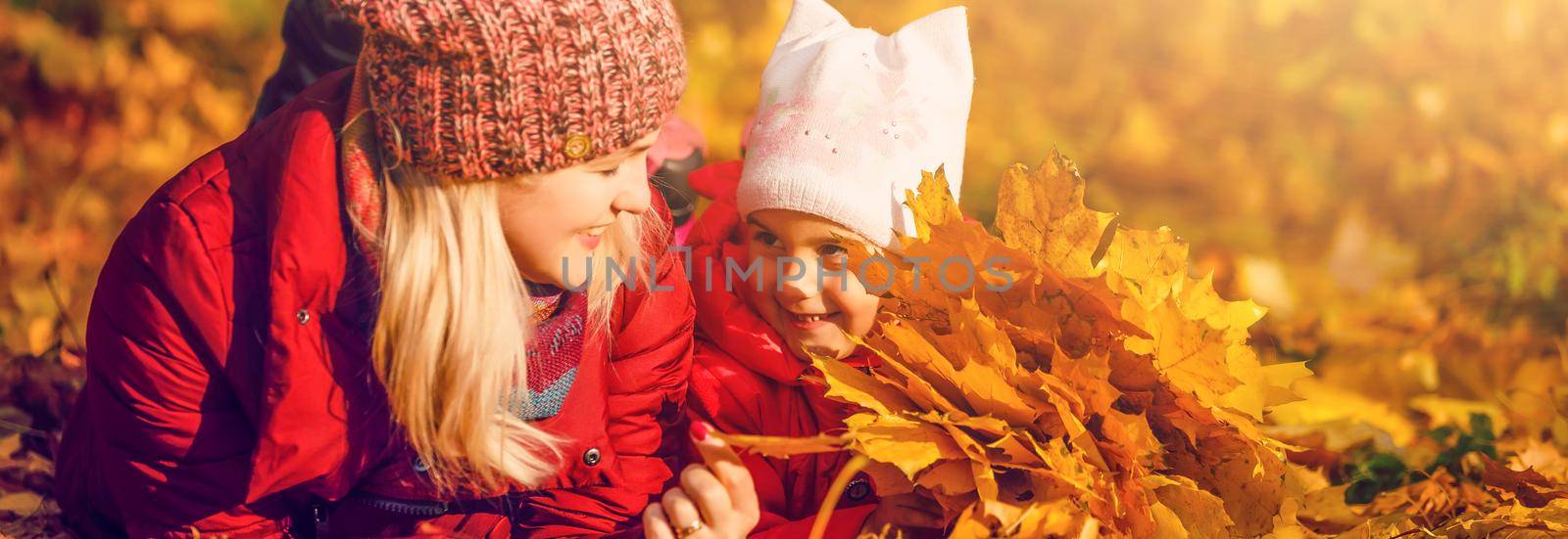 Happy family: mother and child little daughter playing and laughing in the autumn on the nature walk outdoors