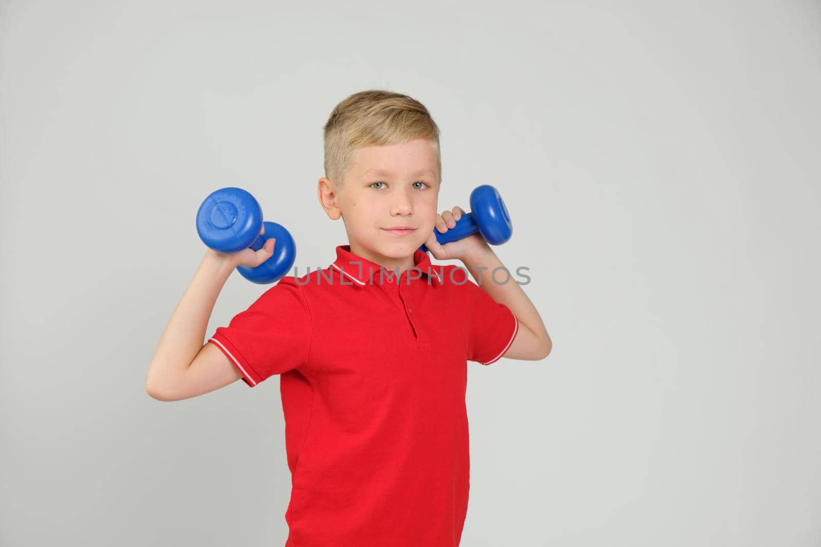 Cool 7 year old blond sporty boy with dumbbells. Sport, health and physical Culture Concept by natus111