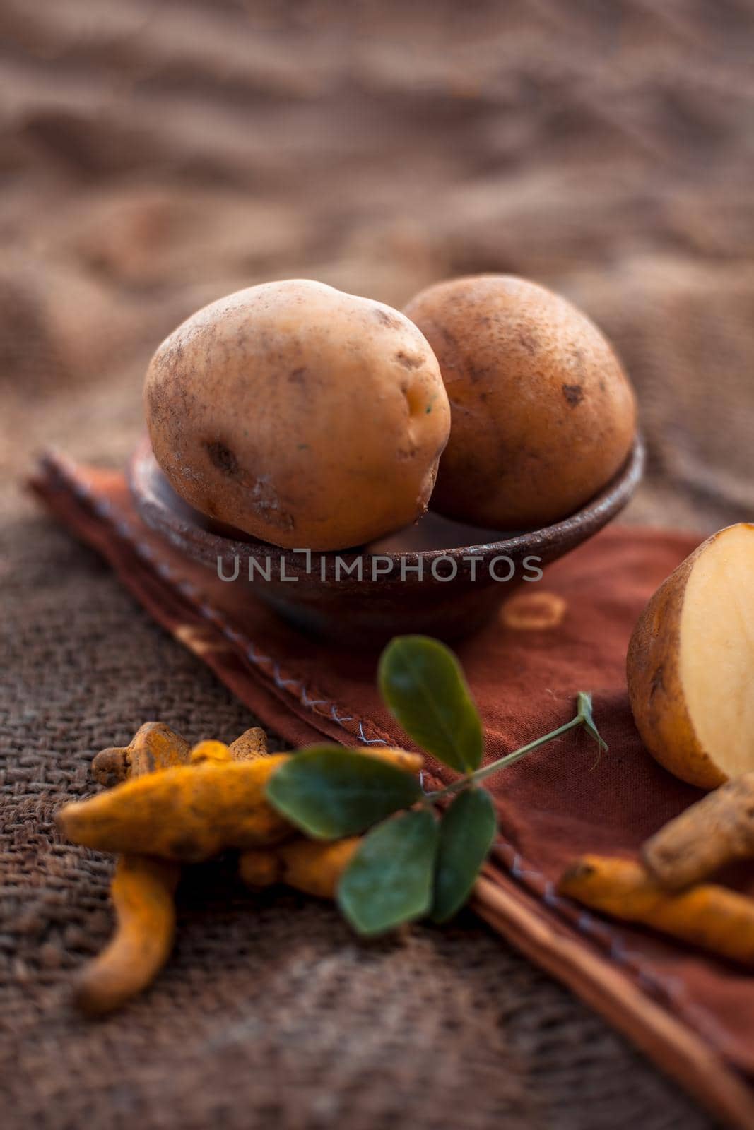 Potato face mask consisting of grated potato and some turmeric powder or haldi in a glass bowl on jute bags surface to brighten the skin, kills bacteria and germs. by mirzamlk