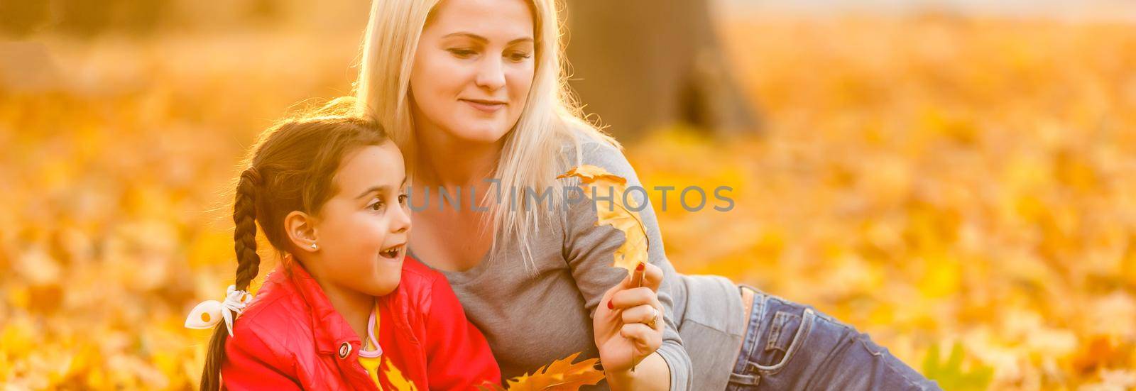 Young mother playing with her daughter in autumn park by Andelov13