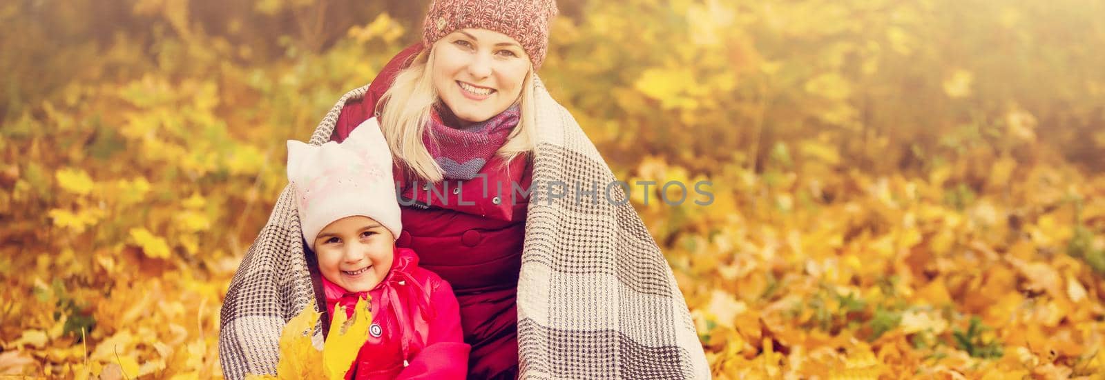 Mother and child hands drink tea in the autumn park in the middle of the orange fallen leaves