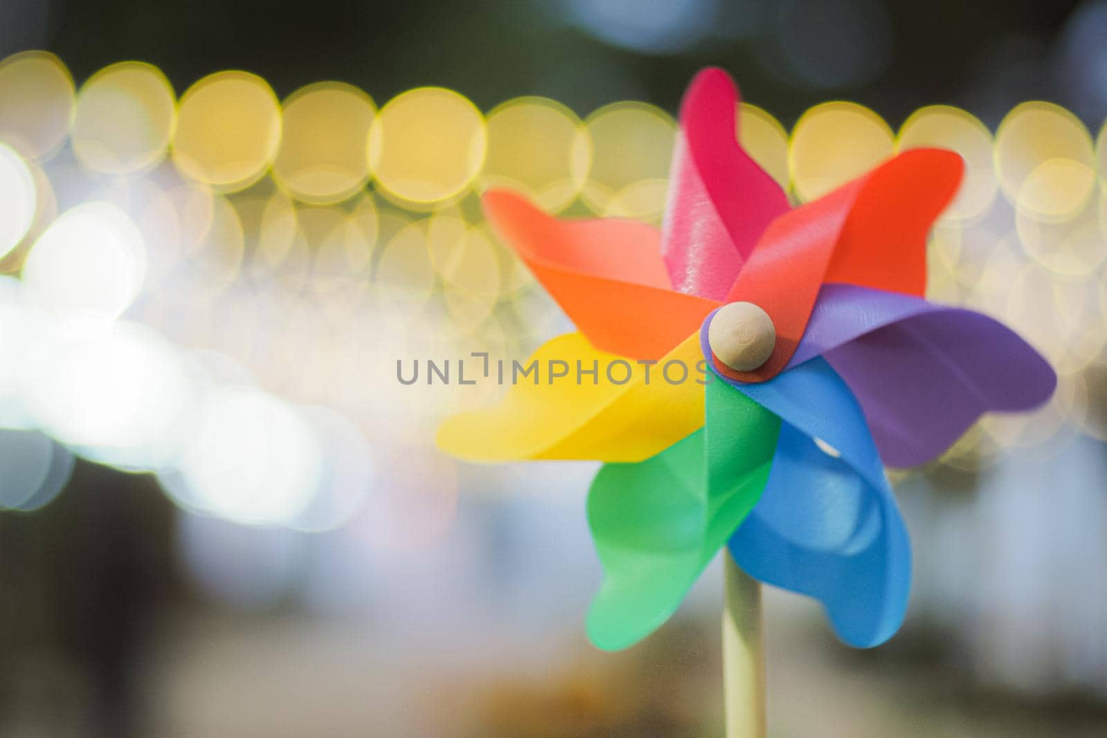 Colorful pinwheel with golden bokeh background. Toy for education nature phenomenon.