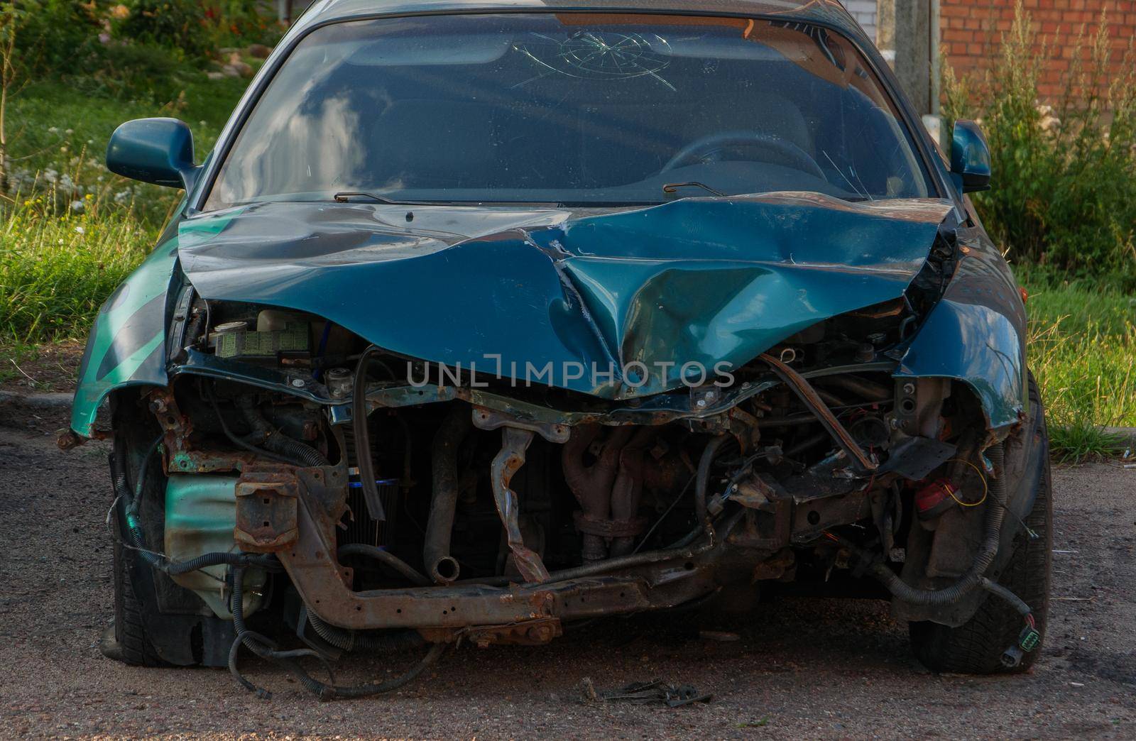 A blue car with a badly damaged bumper.