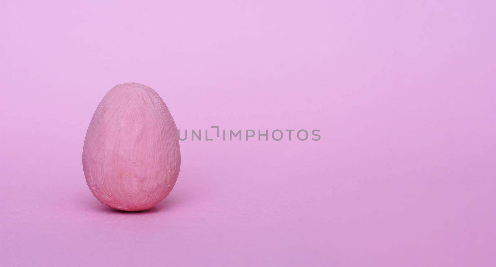 Dark pink decorative egg on a red background. Happy Easter background. Minimal Easter.