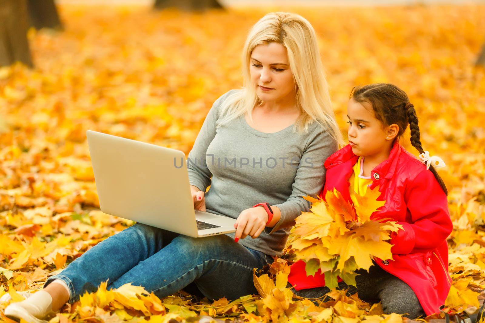 Urban woman and daughter with laptop in park. slim hipster woman in jeans using notebook. freelancer using communication technology remote work and eco-friendly lifestyle. by Andelov13