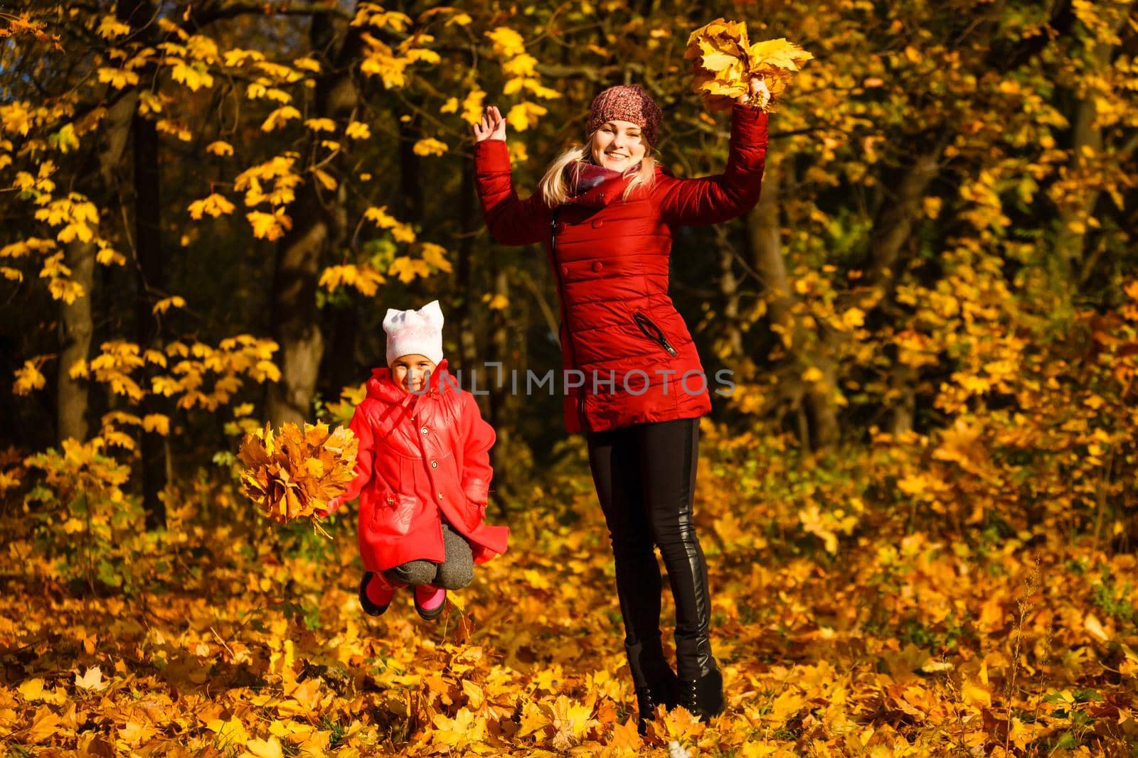 Young mother playing with her daughter in autumn park by Andelov13