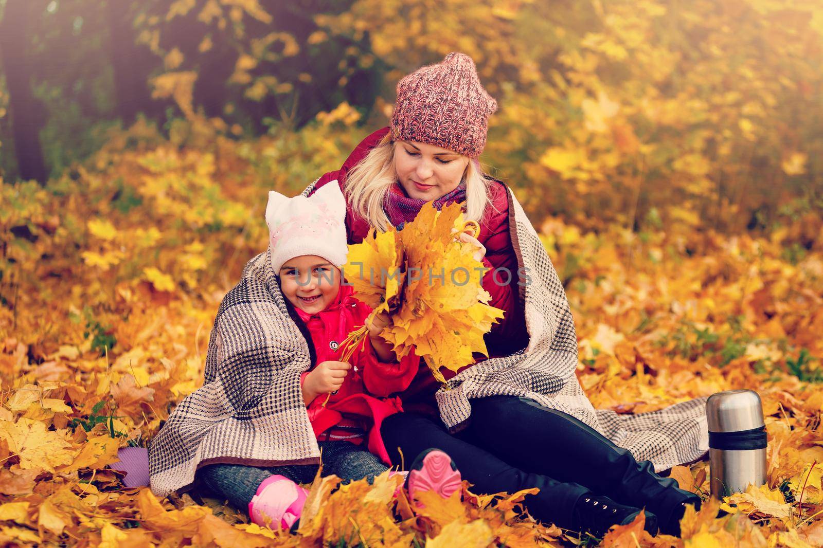 Mother and child hands in the autumn park in the middle of the orange fallen leaves