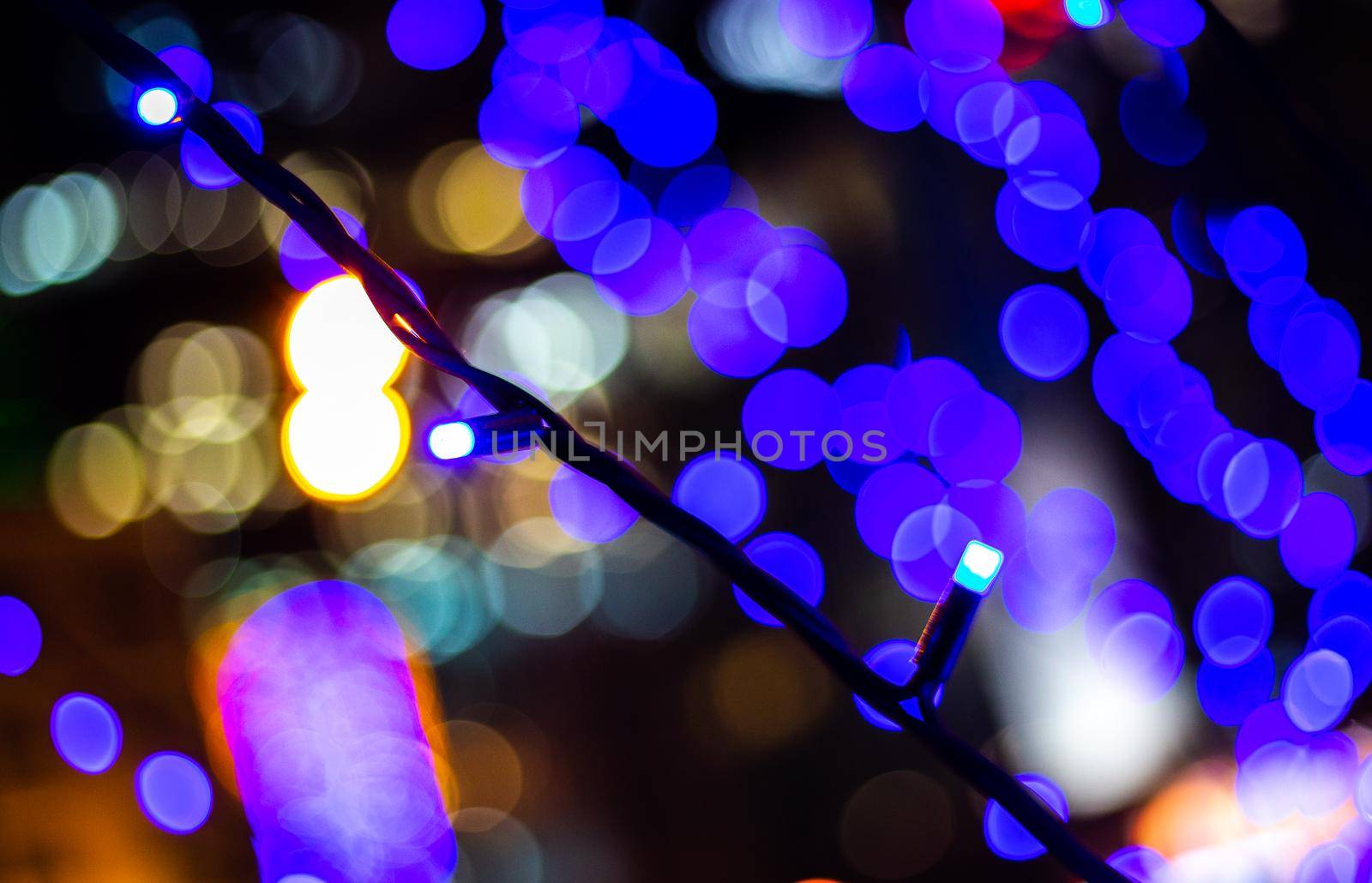 Blurred photo shows Illumination bulbs with blue colours. Festive new year lighting