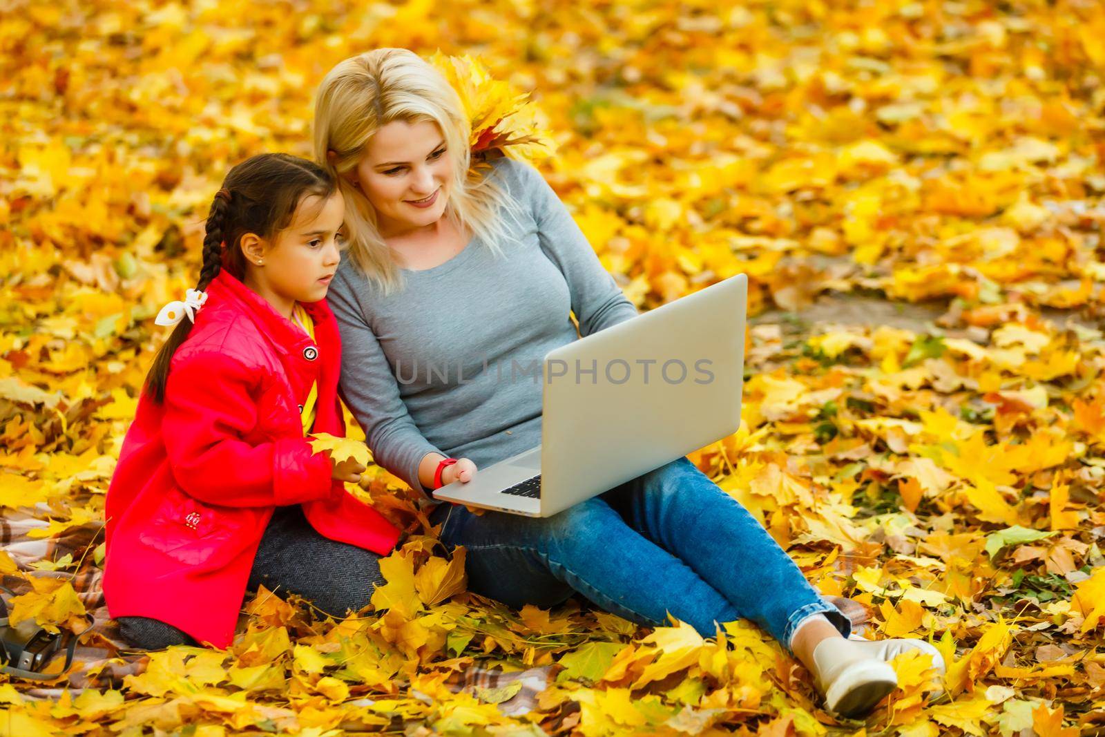 Urban woman and daughter with laptop in park. slim hipster woman in jeans using notebook. freelancer using communication technology remote work and eco-friendly lifestyle. by Andelov13