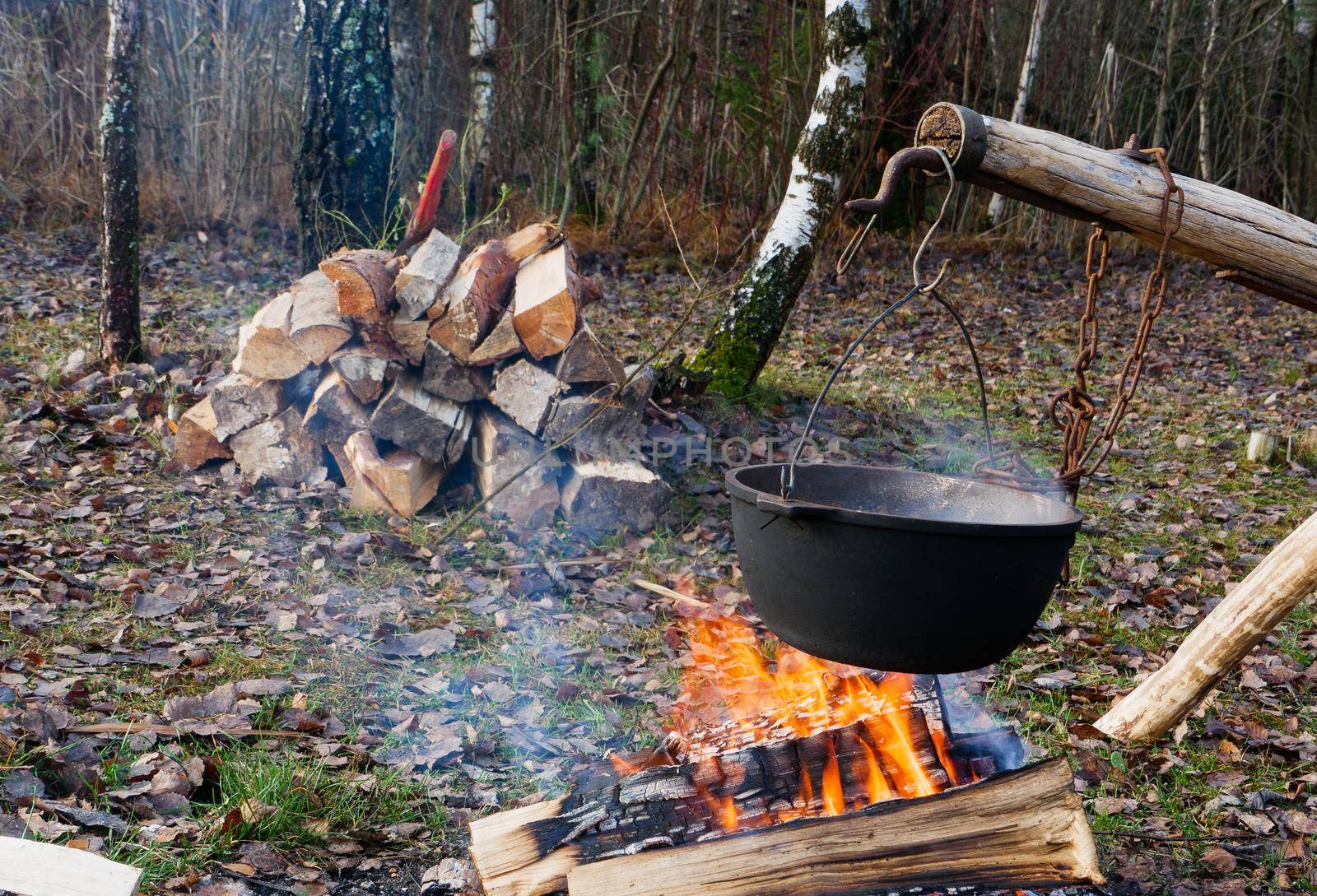 Cooking food in field conditions in a cauldron over a fire. by gelog67