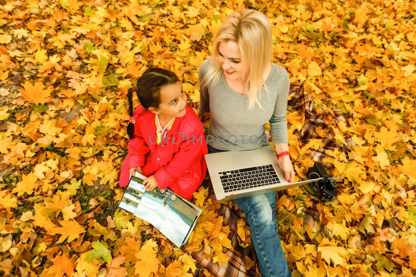 Urban woman and daughter with laptop in park. slim hipster woman in jeans using notebook. freelancer using communication technology remote work and eco-friendly lifestyle. by Andelov13