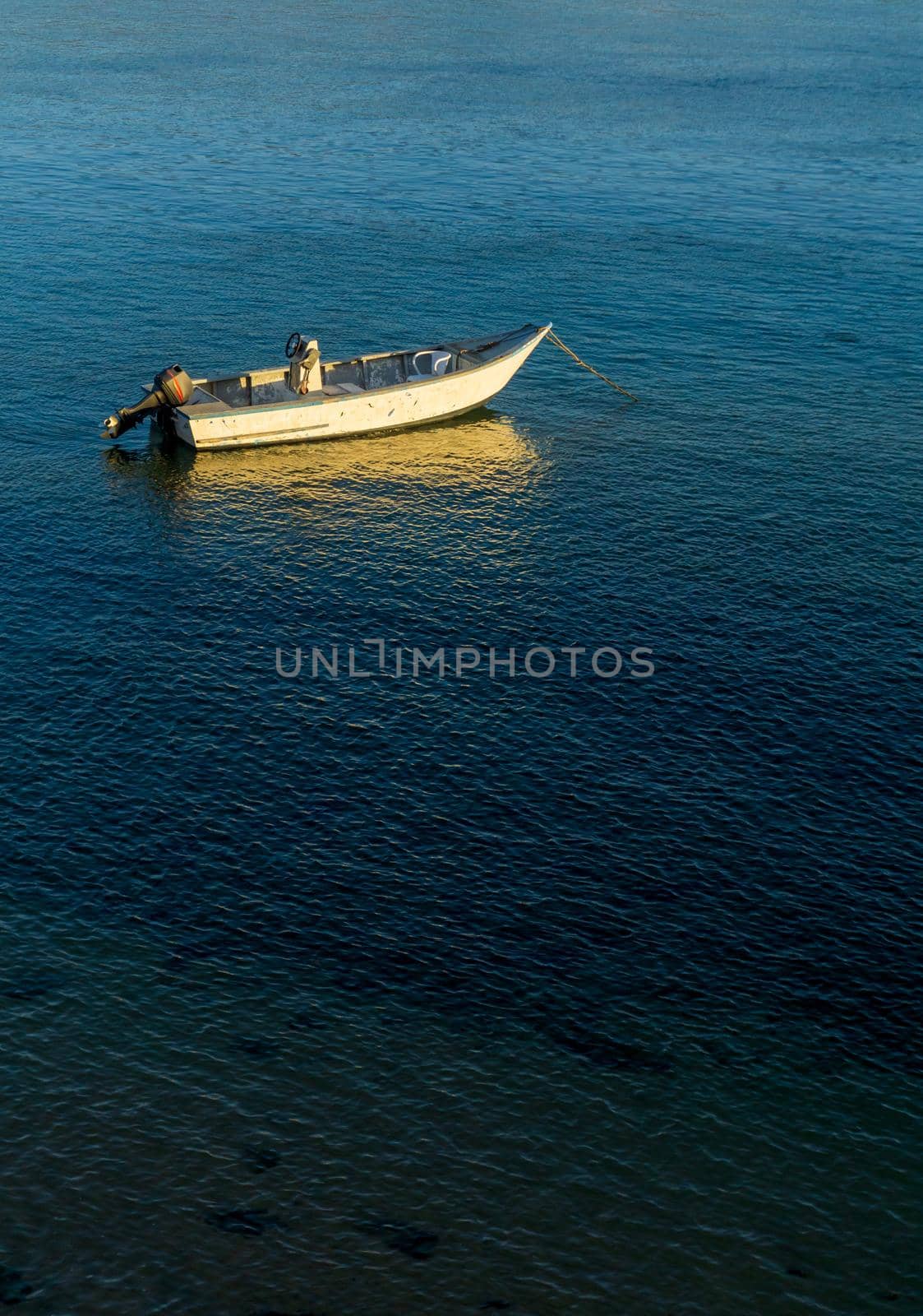 An old motor boat is anchored in the bay at sunset