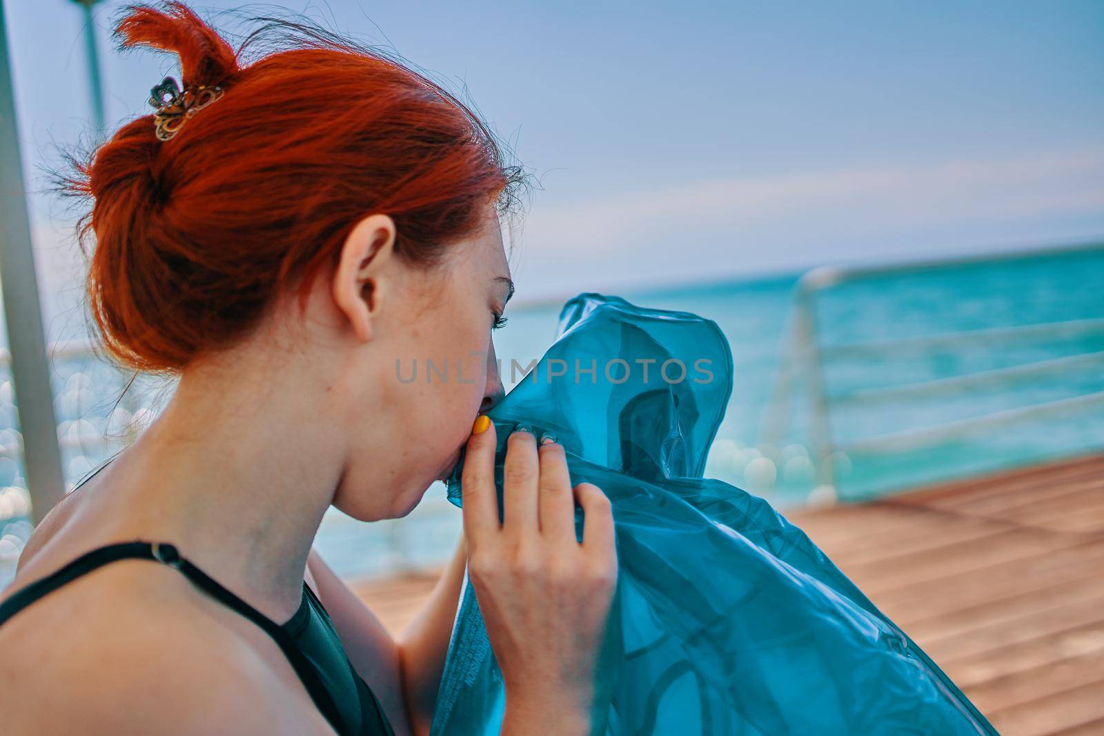 Woman holding inflatable air mattress. Woman inflates donut for swimming.