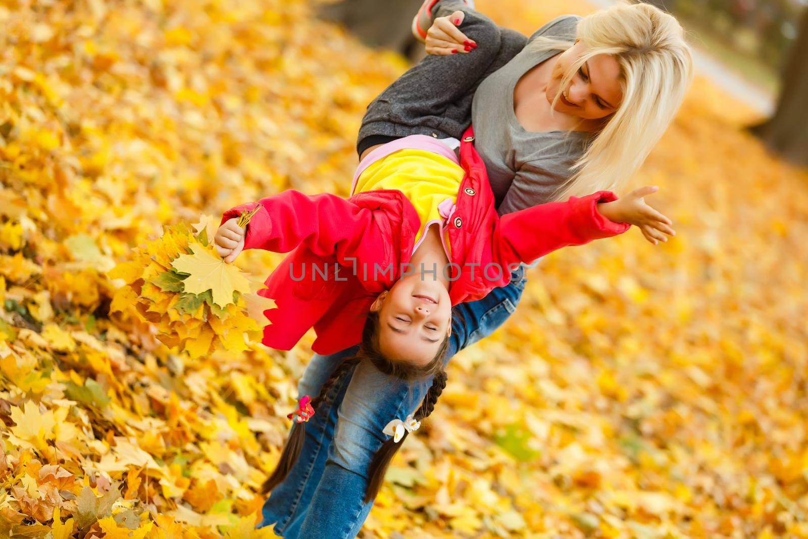Happy family: mother and child little daughter play cuddling on autumn walk in nature outdoors
