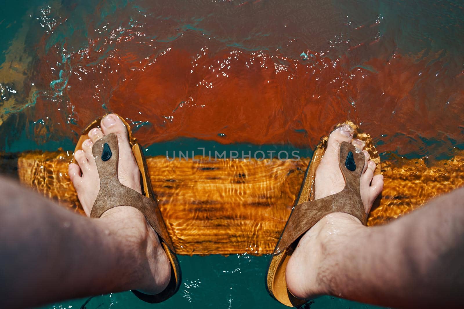 Legs in water. A young mans legs together over a pier in ocean.