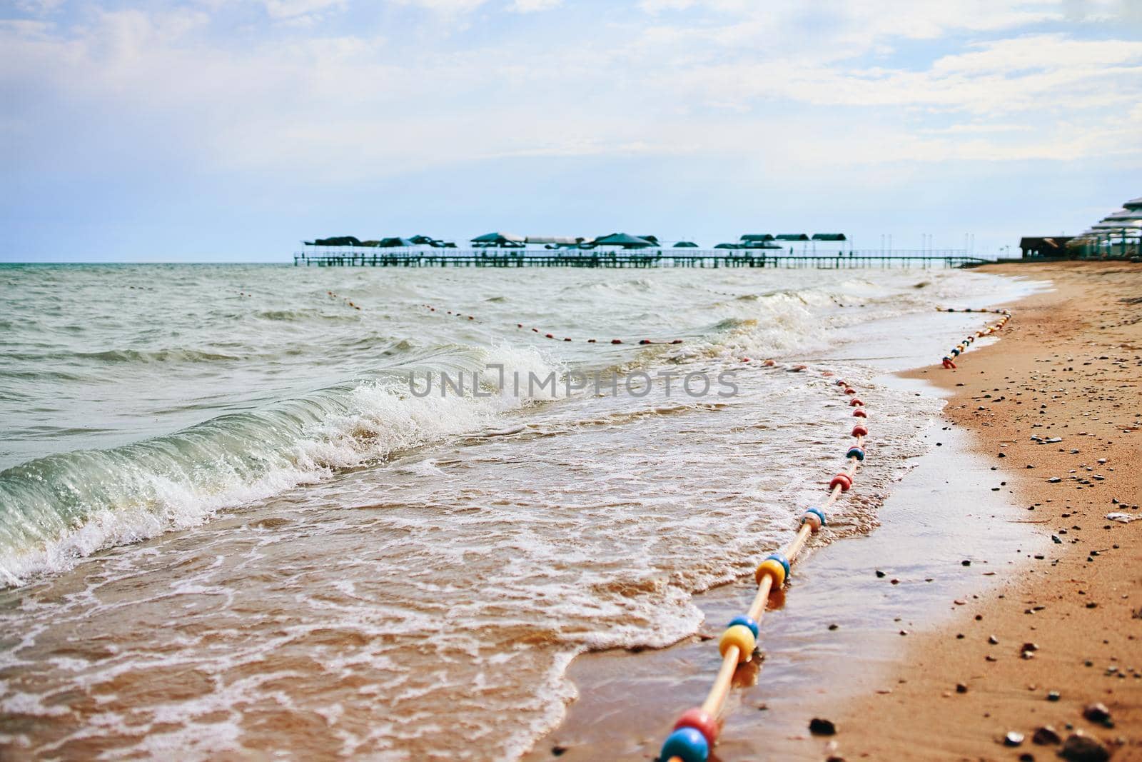 Sandy beach with waves from the sea. Vacation by the ocean in the hotel.