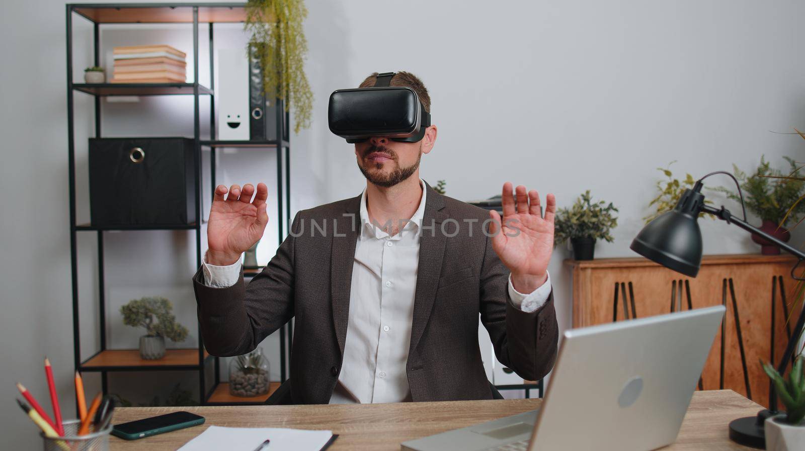 Businessman in suit working using virtual reality futuristic technology VR app headset helmet at home office. Freelancer man busy creating new architecture project. Remote education, study, learning