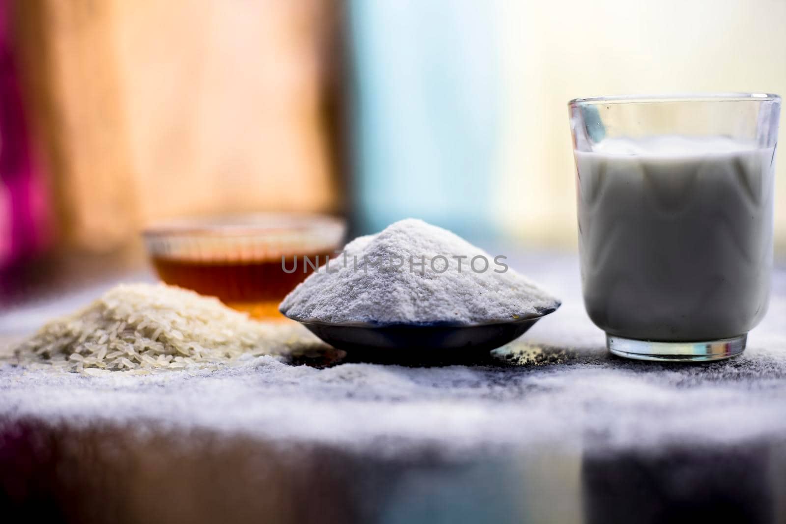 Face mask for flawless skin on wooden surface consisting of rice flour,corn flour,honey,milk, in a glass bowl and entire raw ingredients present on the surface.