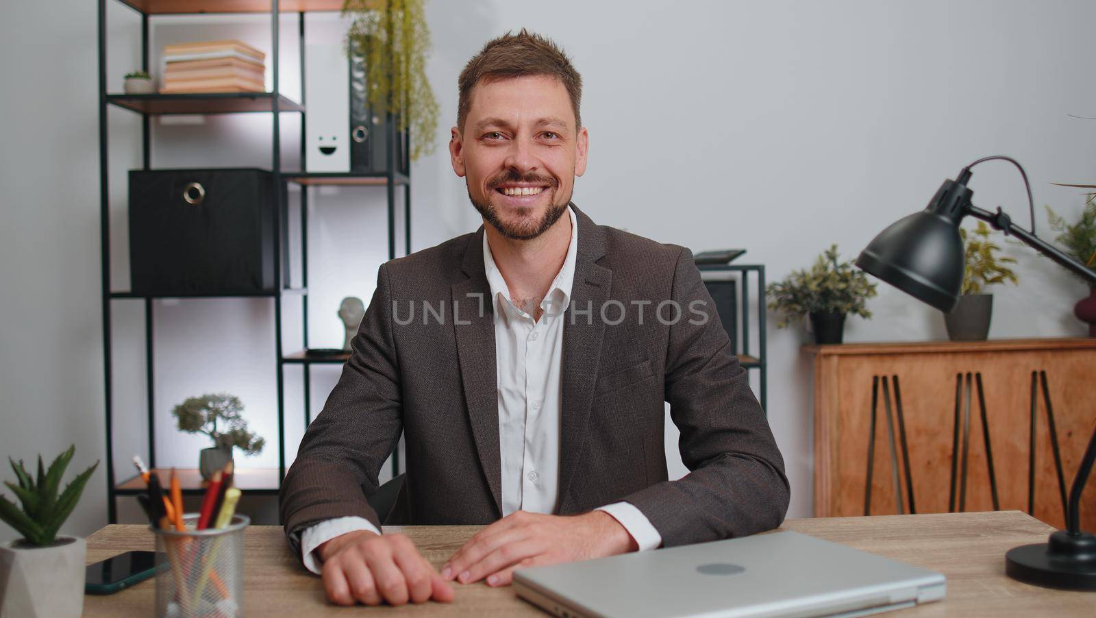 Businessman in suit closing laptop pc computer after finishing work at home office desk. Smiling male manager freelancer man busy working online, remote job. E-learning, browsing internet on notebook