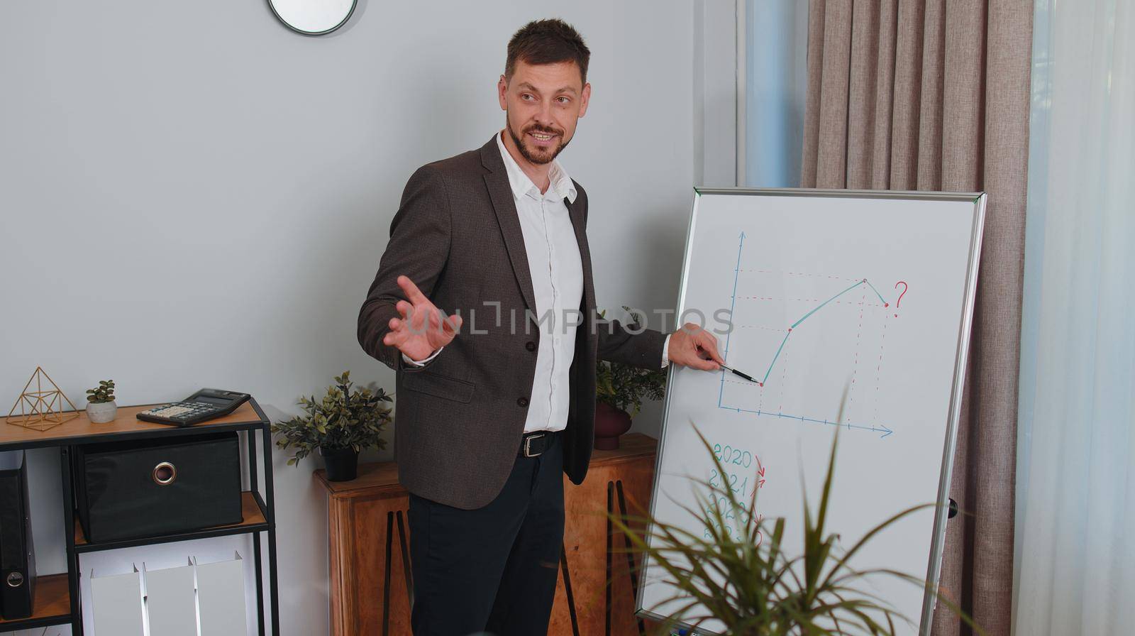 Businessman in formalwear suit holds online meeting presentation or training using a whiteboard at office. Marketing graph growth course. Financial strategy. Business increase. Freelancer business man