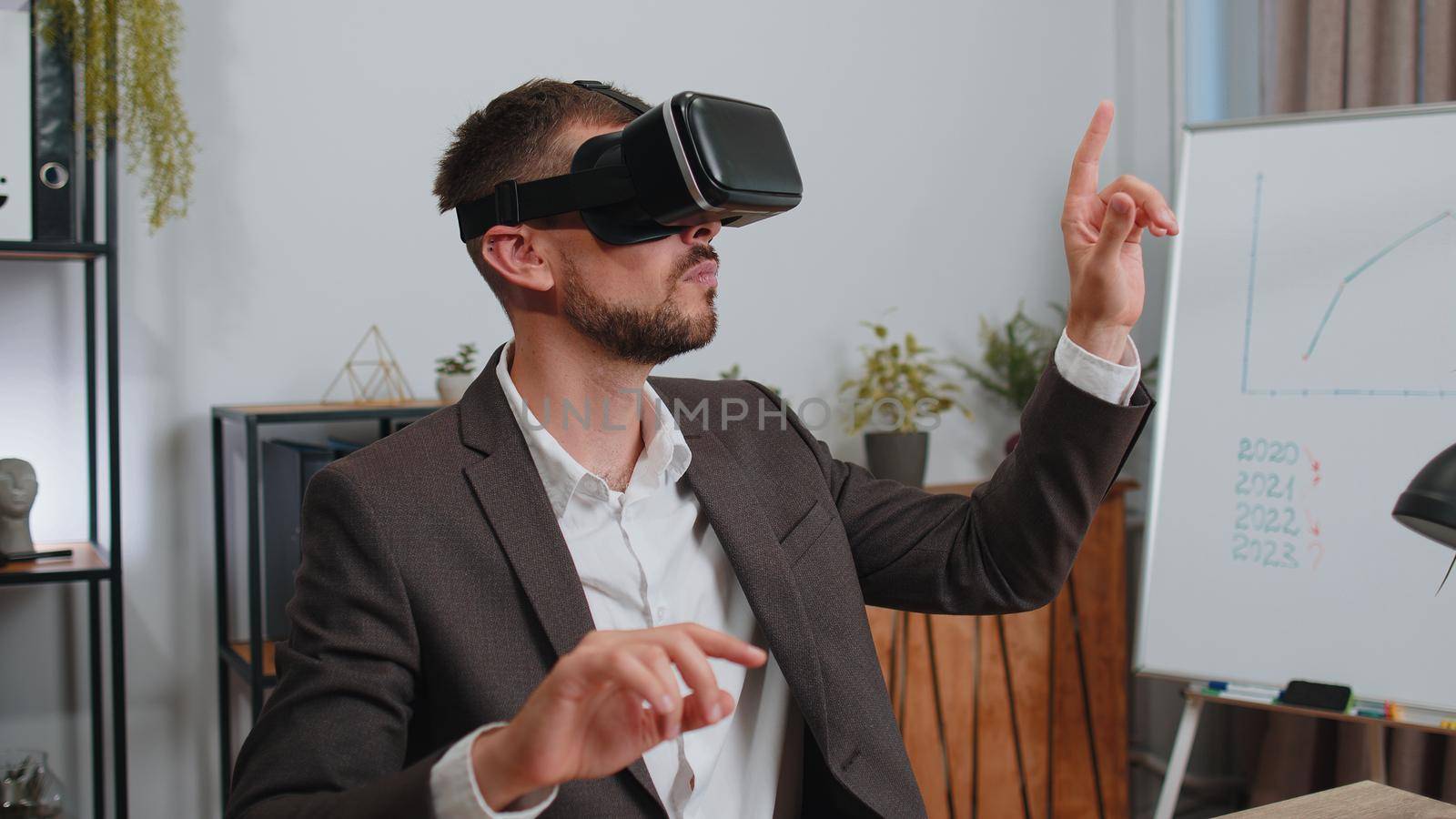 Businessman in suit working using virtual reality futuristic technology VR app headset helmet at home office. Freelancer man busy creating new architecture project. Remote education, study, learning