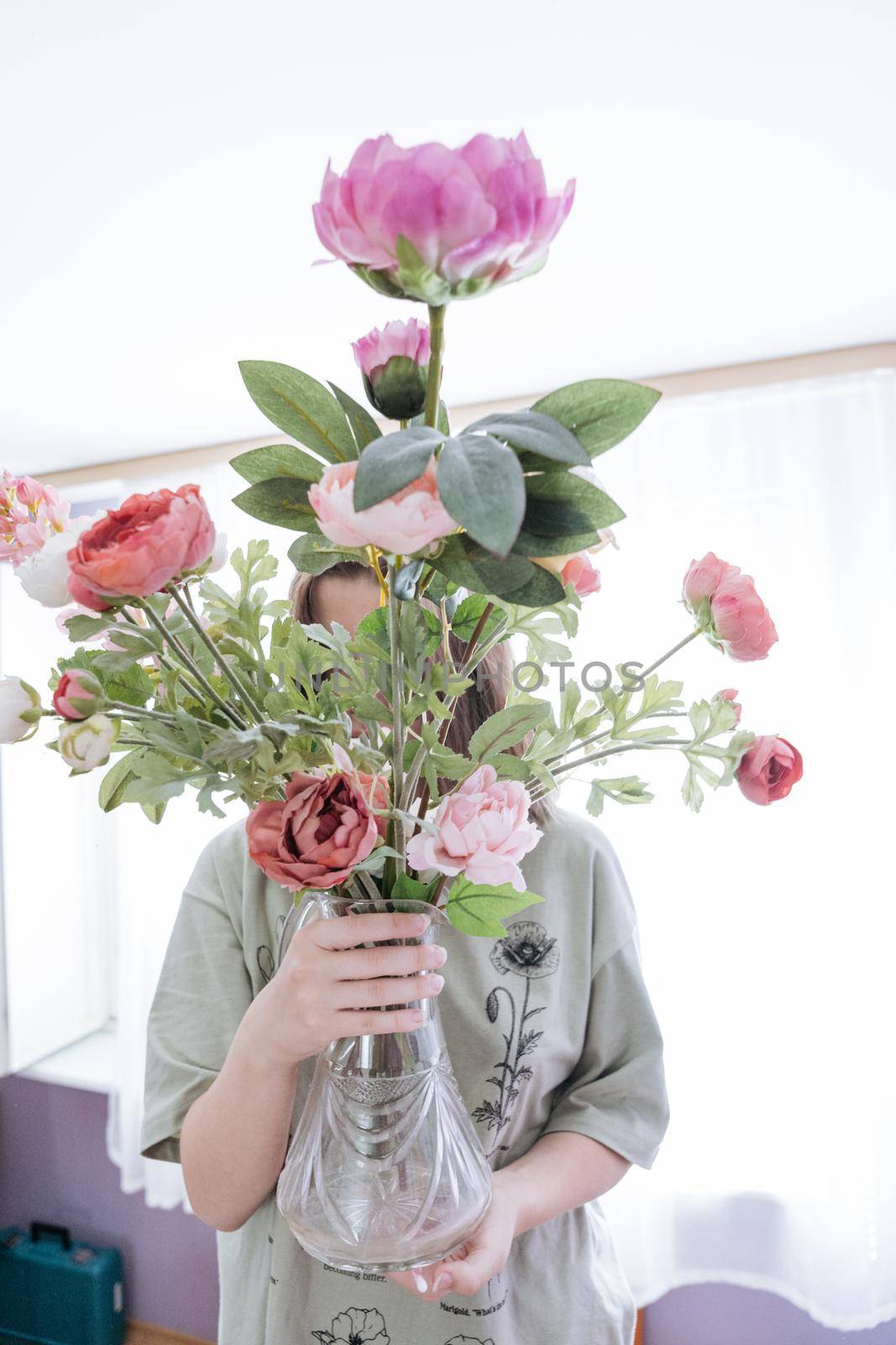 Teenager girl holding a bunch of pink and red peonies in vase by Varaksina