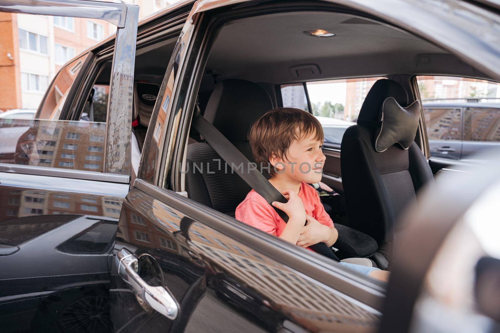 boy wearing pink sitting in he car and looking with curiosity by Varaksina