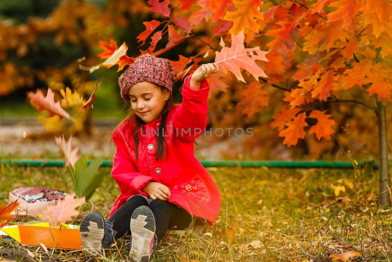 Adorable little schoolgirl studying outdoors on bright autumn day. Young student doing her homework. Education for small kids. Back to school concept.