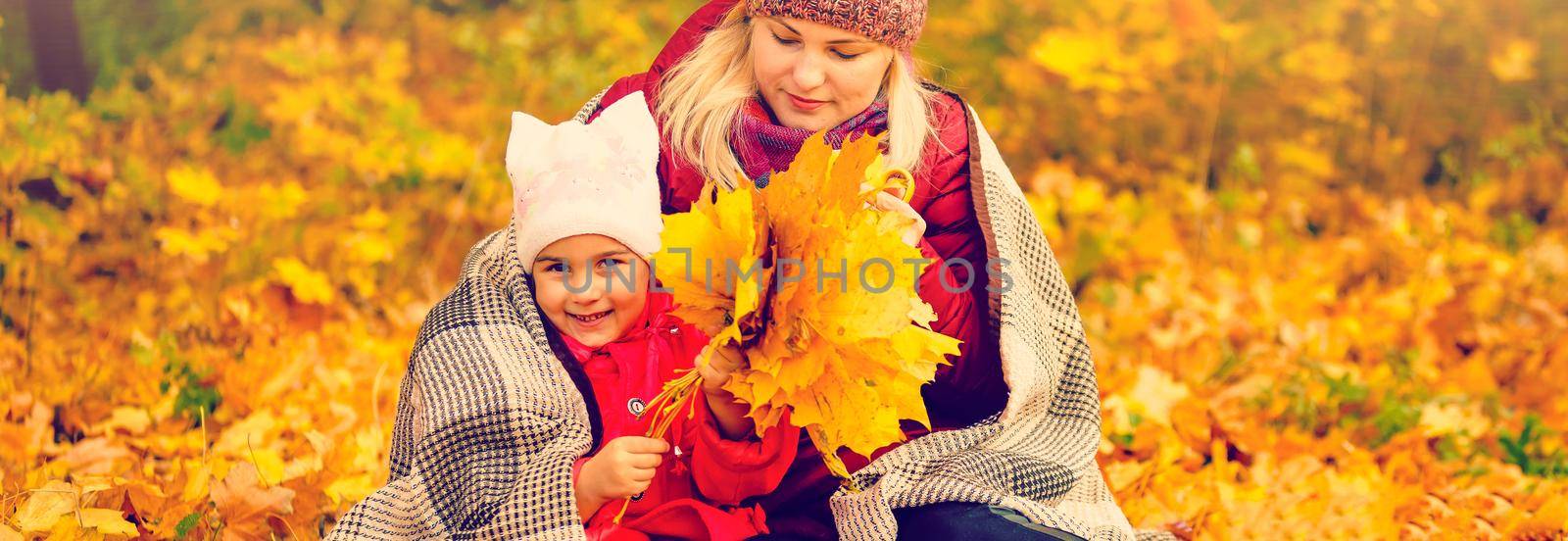 Mother and child hands in the autumn park in the middle of the orange fallen leaves