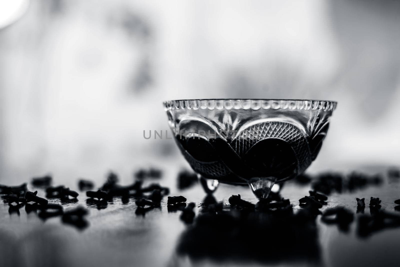 Ready to use apply face mask of clove and its oil in at transparent glass bowl on wooden surface along with some cloves spread on the surface. by mirzamlk