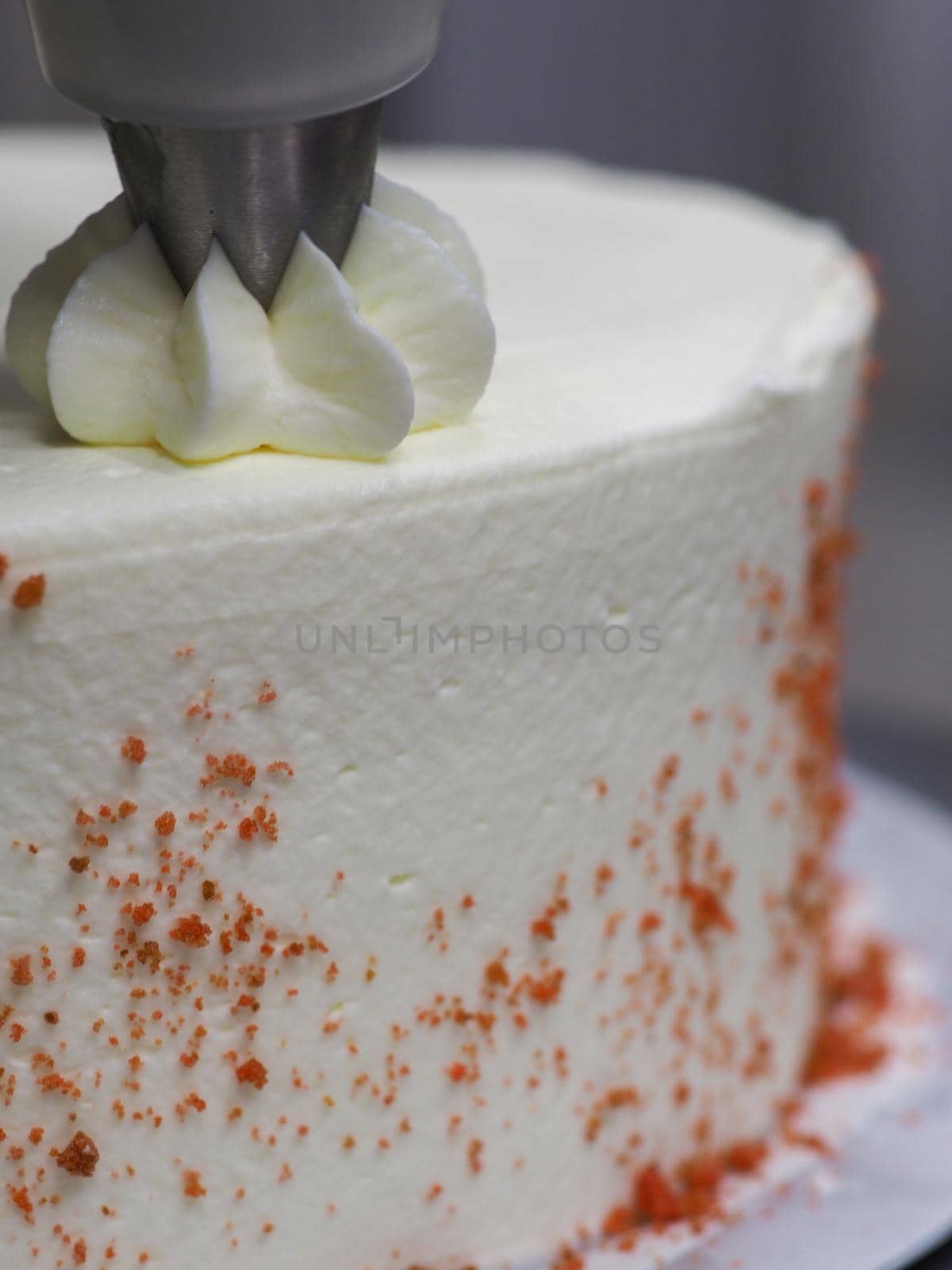 hand pof chef making for icing a red drip cake in the professional kitchen lab