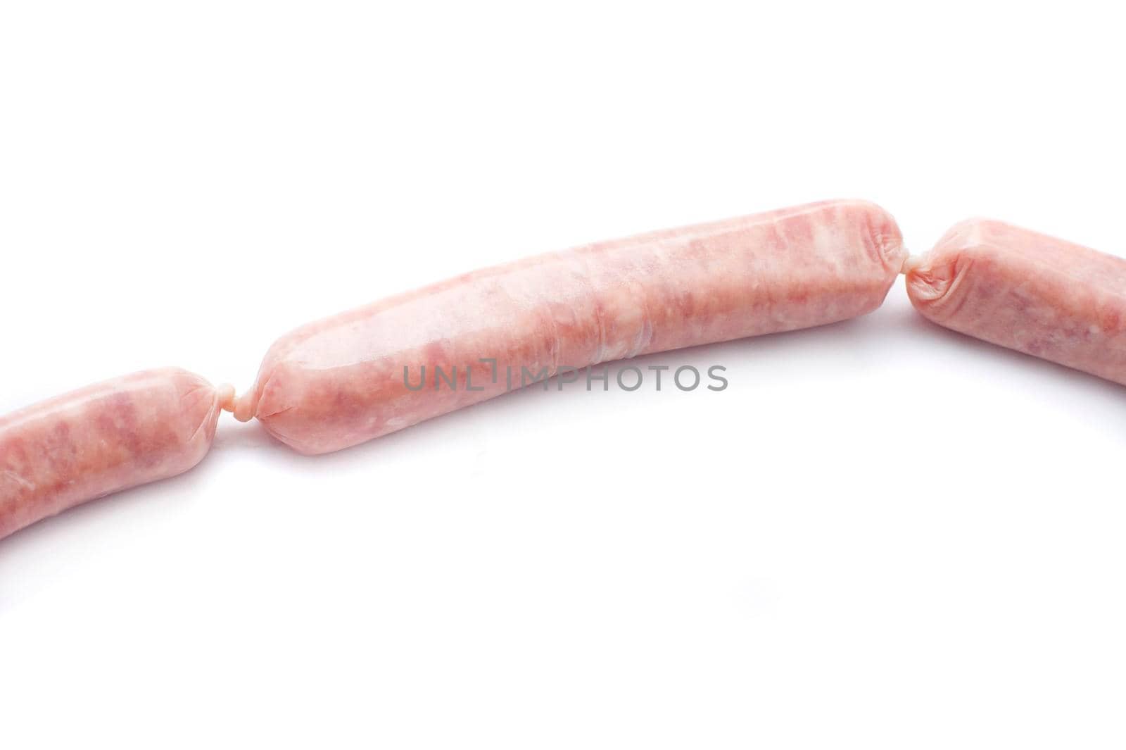 Raw pork sausage linked to two additional sausages , one on either side, over a white background