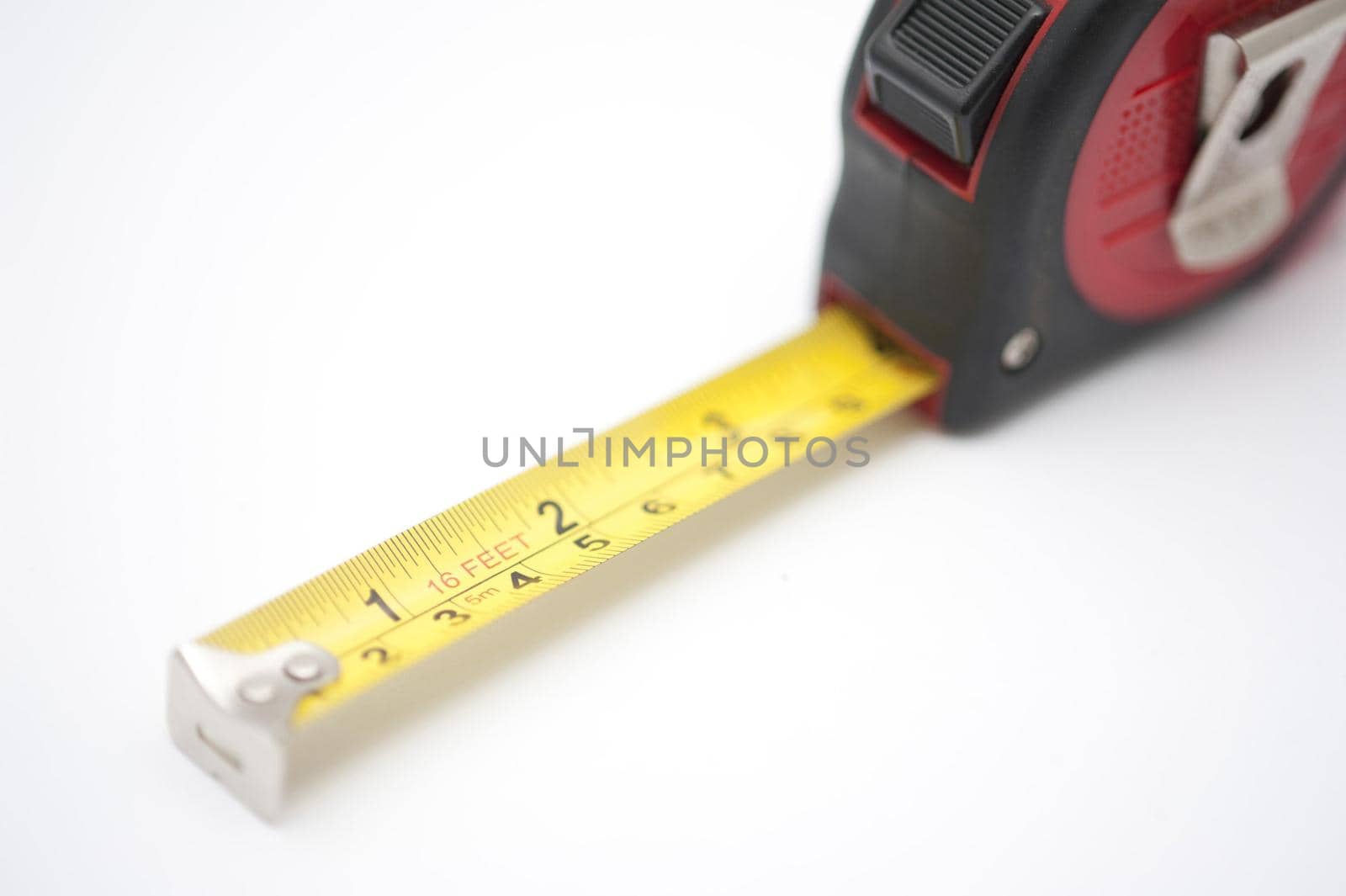 Builders retractable tape measure with centimeters and inches on a white background with part of the tape extended to show the two scales