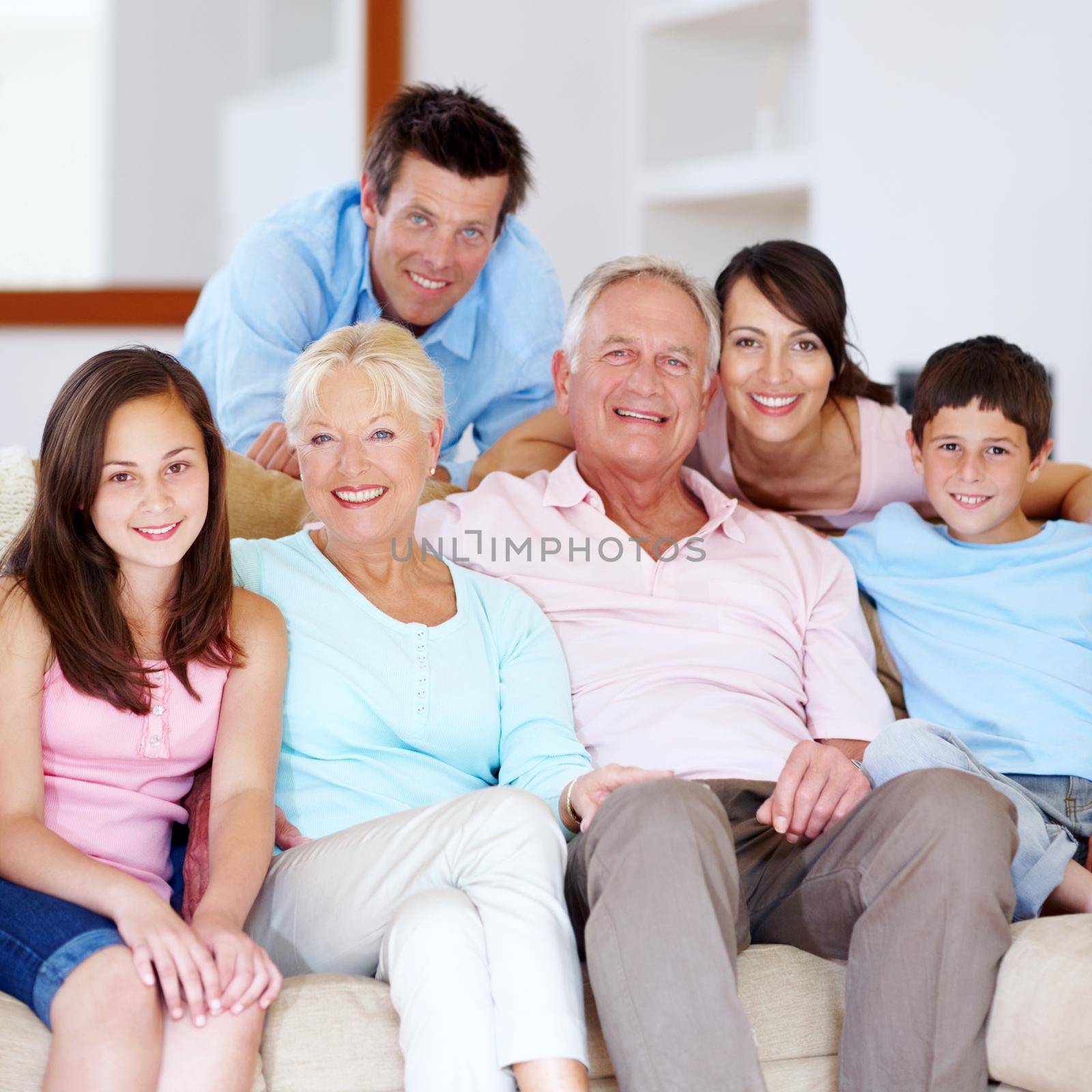 A proud, loving family enjoying time together. Three generations of family embracing one another on the lounge couch
