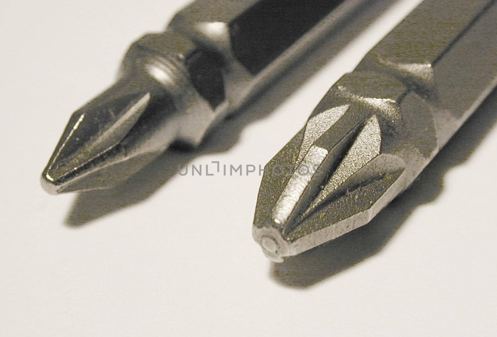 Two new screw bits of Philips and Pozidriv types, viewed in macro close-up on white surface