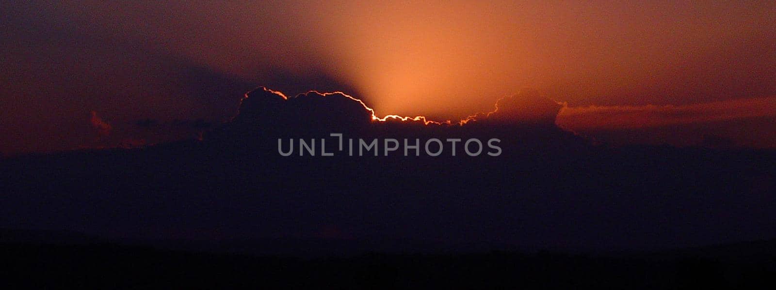 sun breaking through from behind a cloud at sunrise