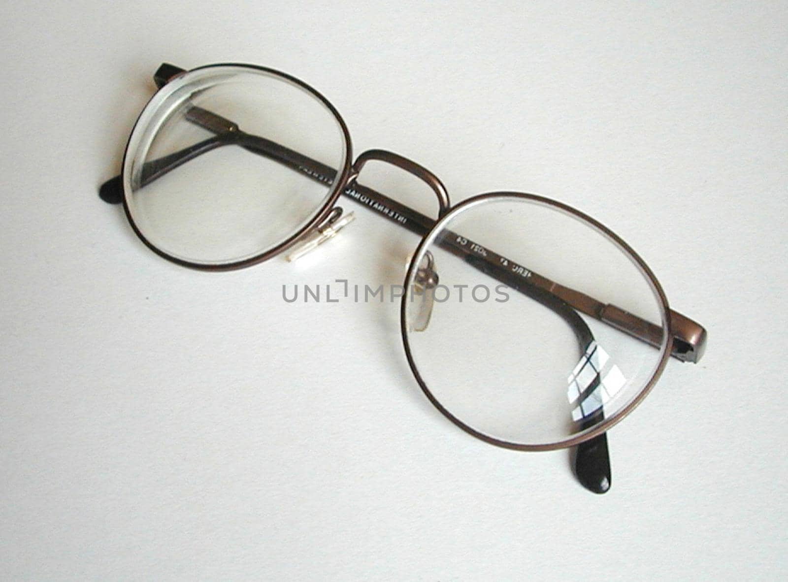 Pair or eyeglasses lying folded on a white background with copy space viewed high angle close up