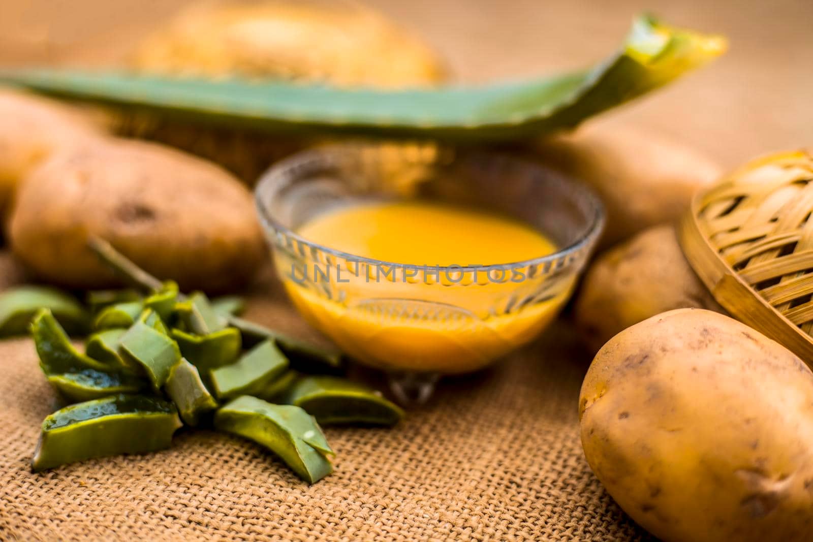 Homemade conditioner and shampoo for dandruff and scalp cleaning on jute bag's surface i.e. potato juice well mixed with aloe vera gel in a glass bowl along with raw potato and some aloe vera leaf.