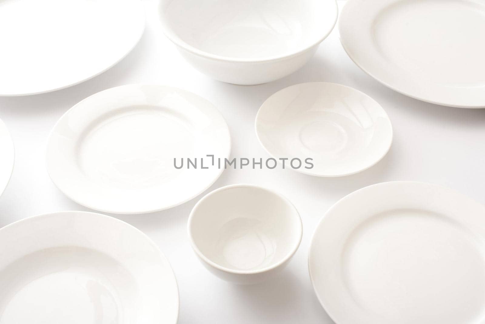Plain clean empty generic white tableware over a white background with assorted plates and bowls in a full frame background
