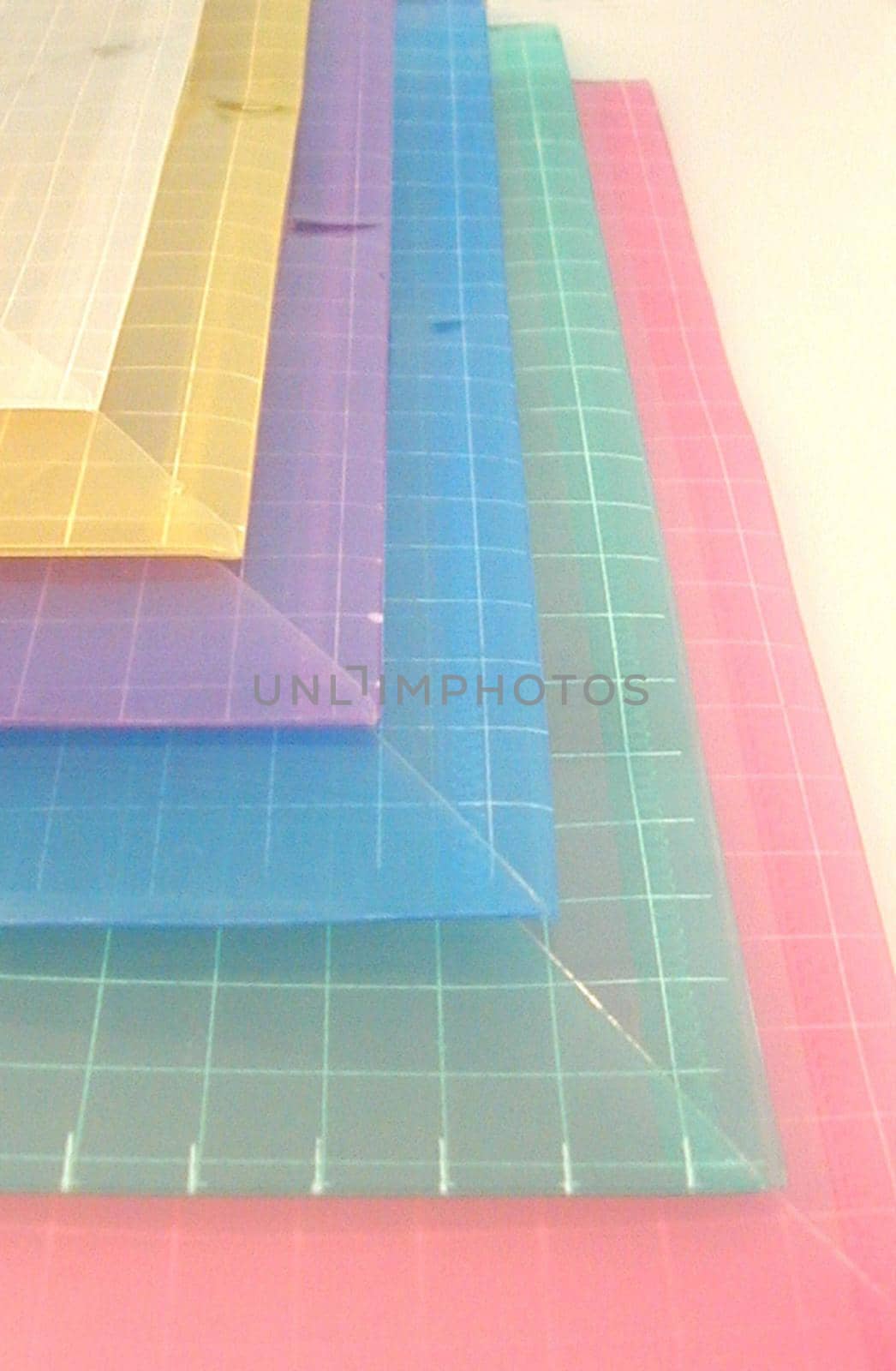 Sheets of colorful plastic viewed one on top of the other in a staggered arrangement of the corners for a decorative pattern