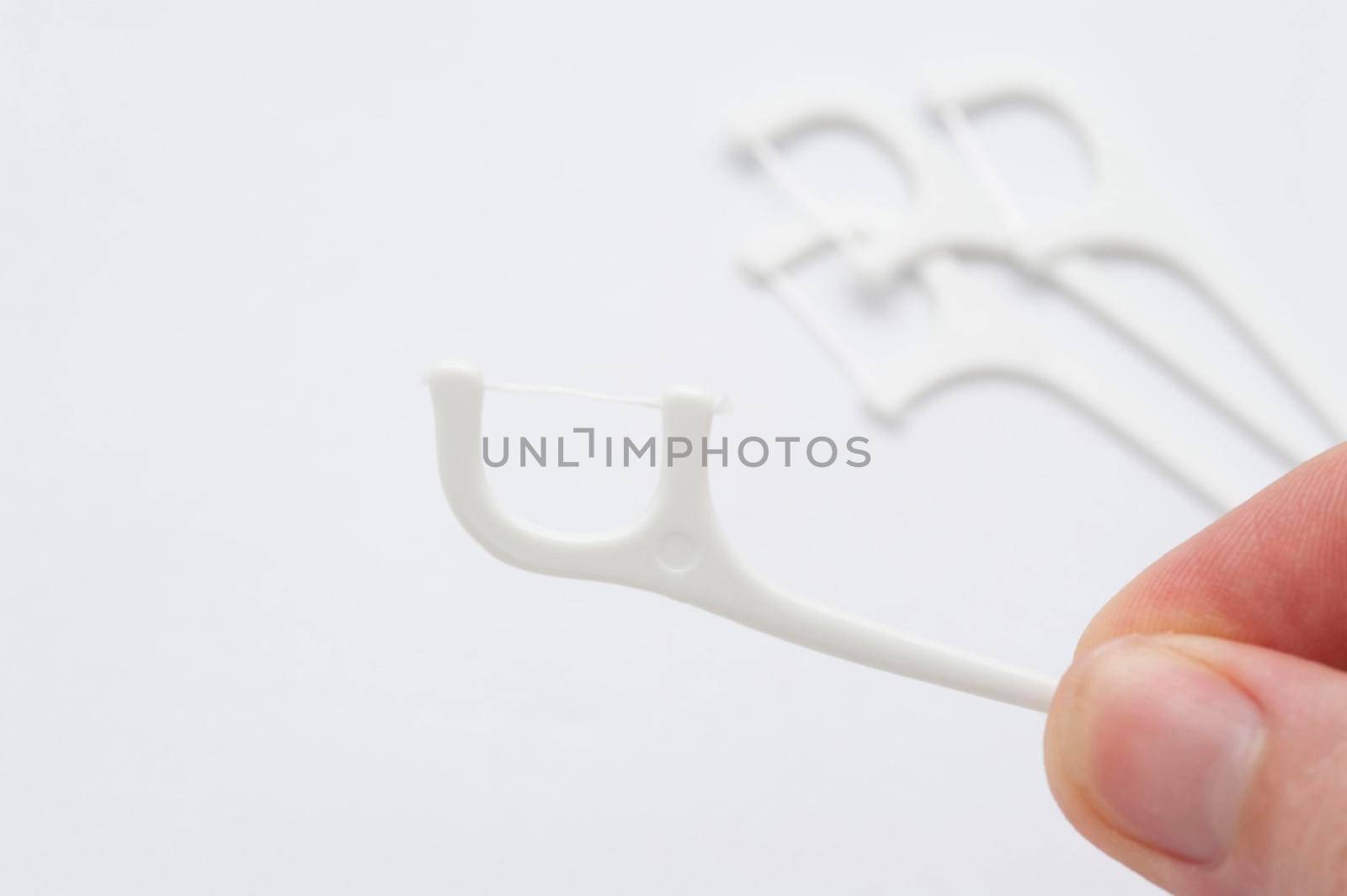 close up on a hand holding a dental flossing tooth pick