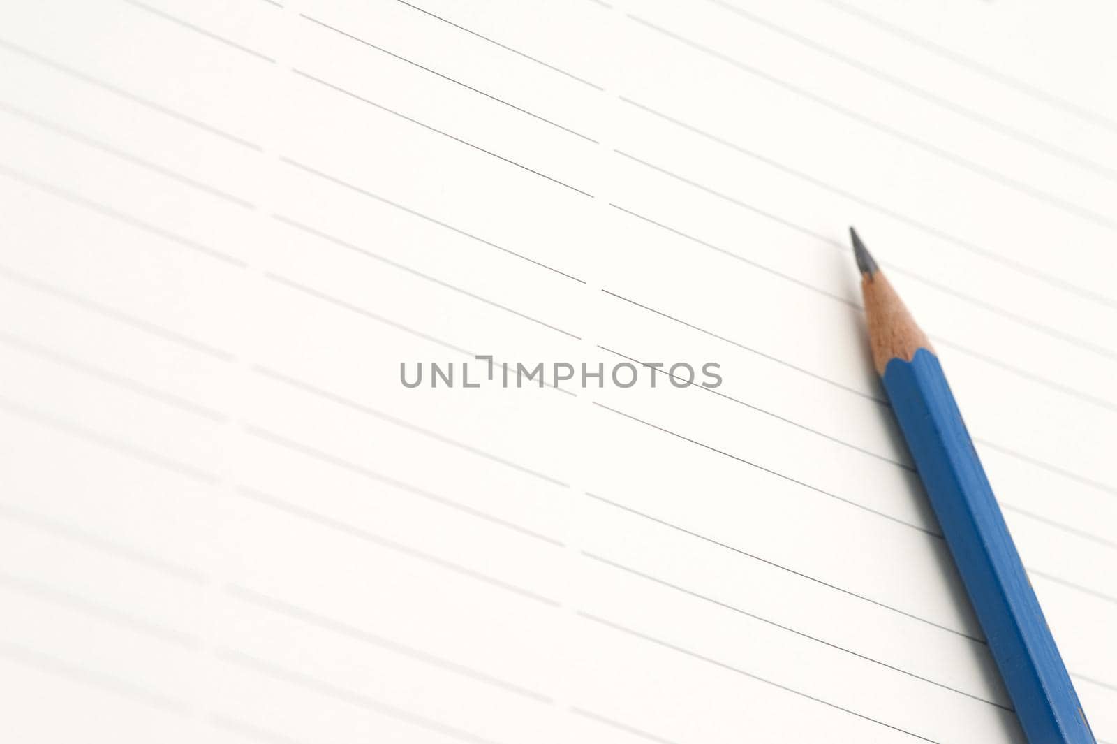 Sharp blue pencil on lined paper with space to place your message or text between the lines