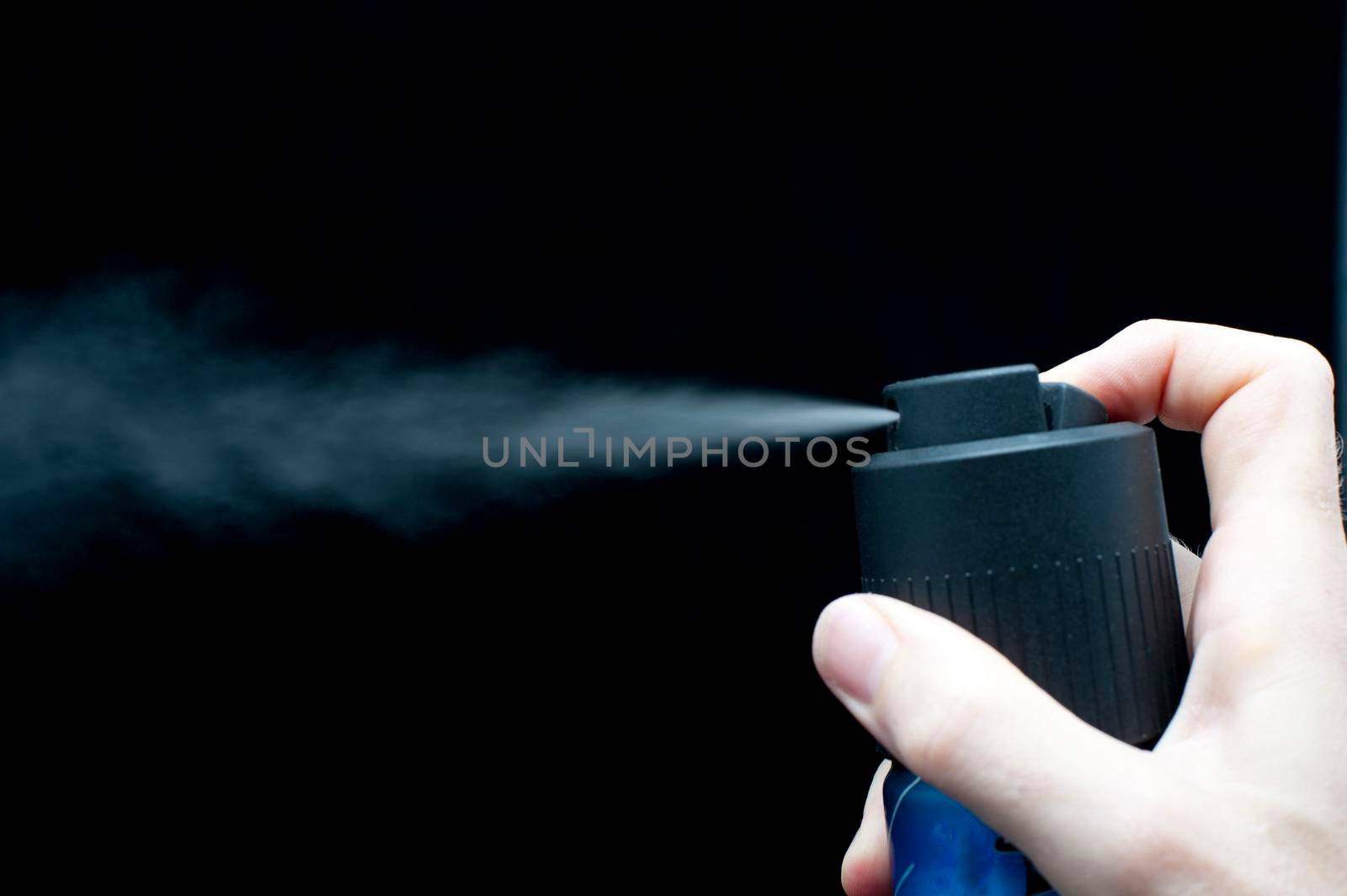 spraying a can of deodorant on a black background