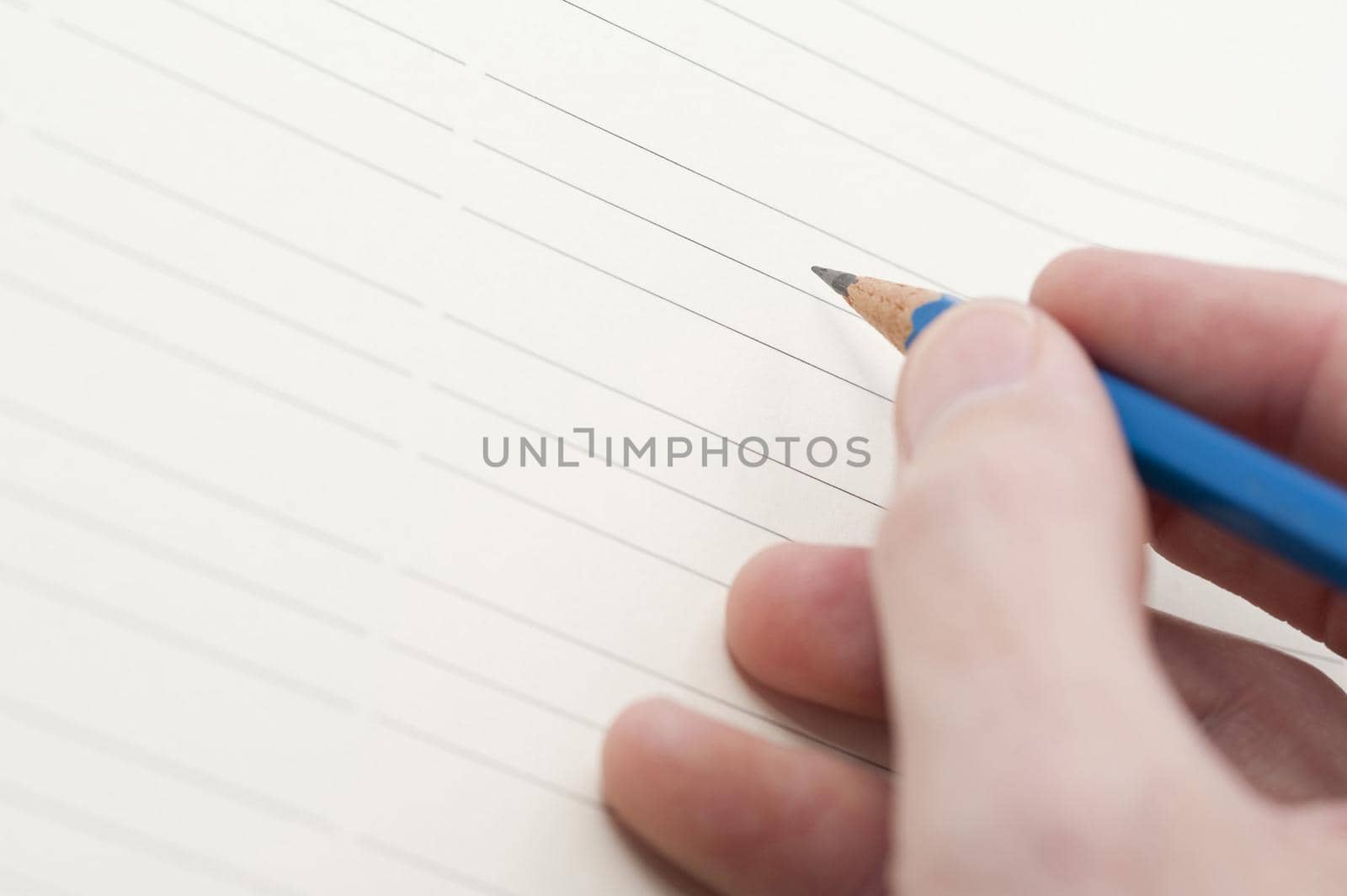 Hand holding pencil ready to write your message or text on a blank lined sheet of paper