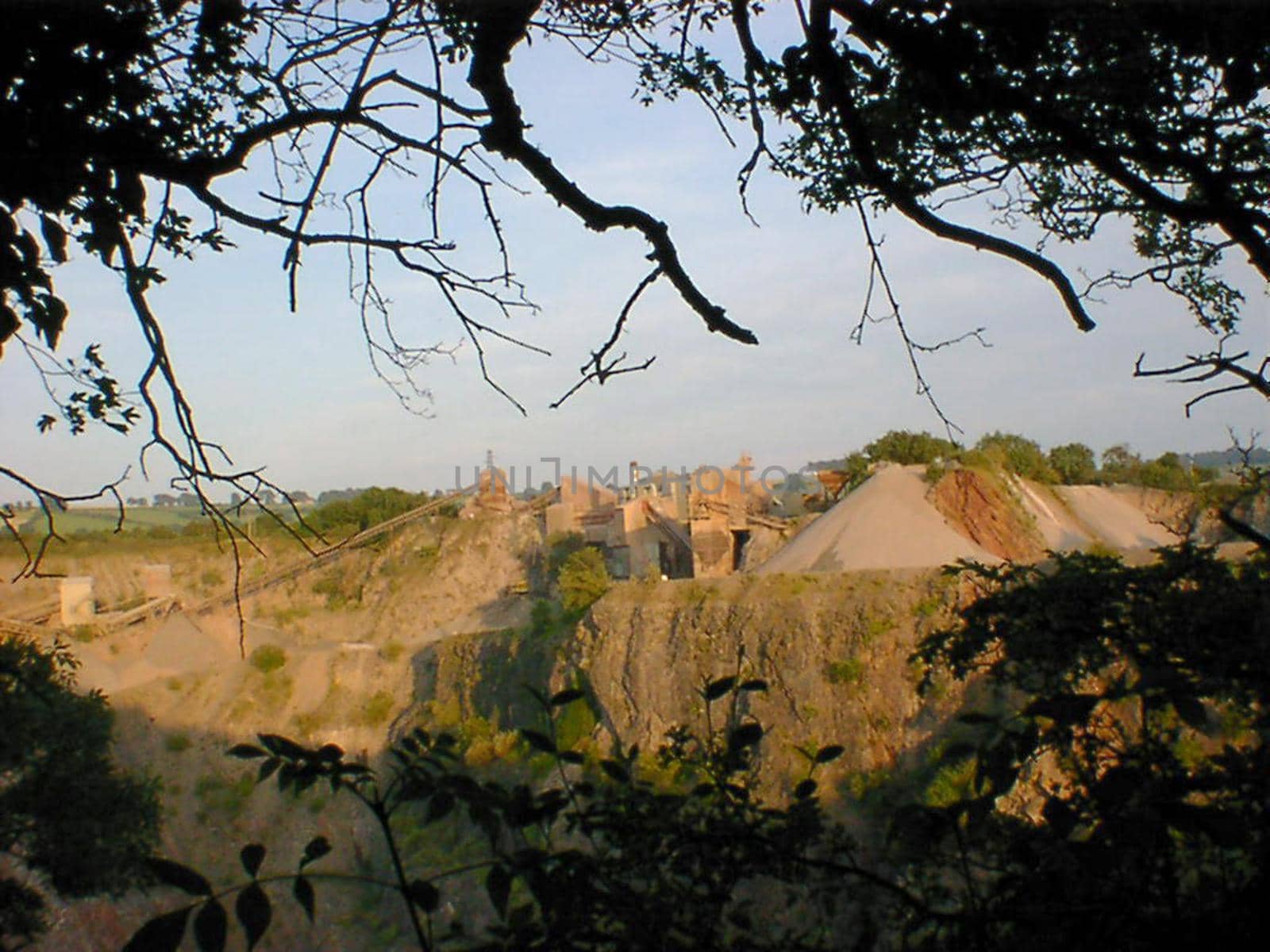 View of an open cast quarry through trees in an concept of exploiting natural resources, mining and industry