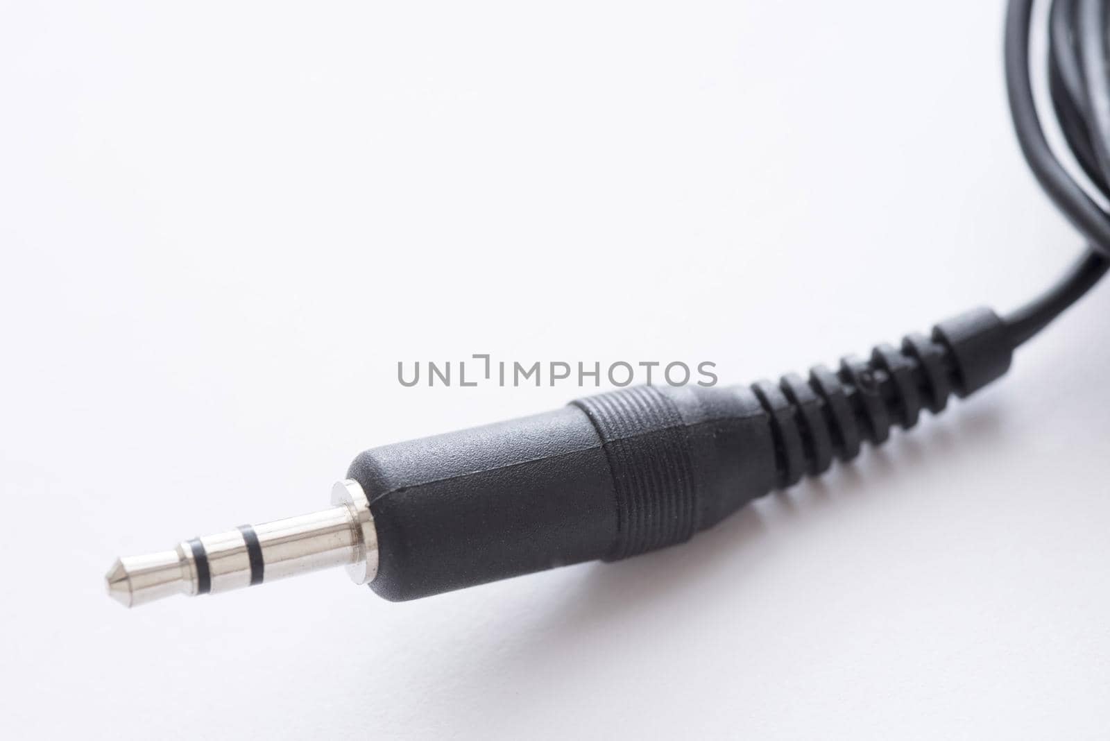 Audio jack 3.5 mm stereo plug with black cord in plastic body close-up on white background with copy space